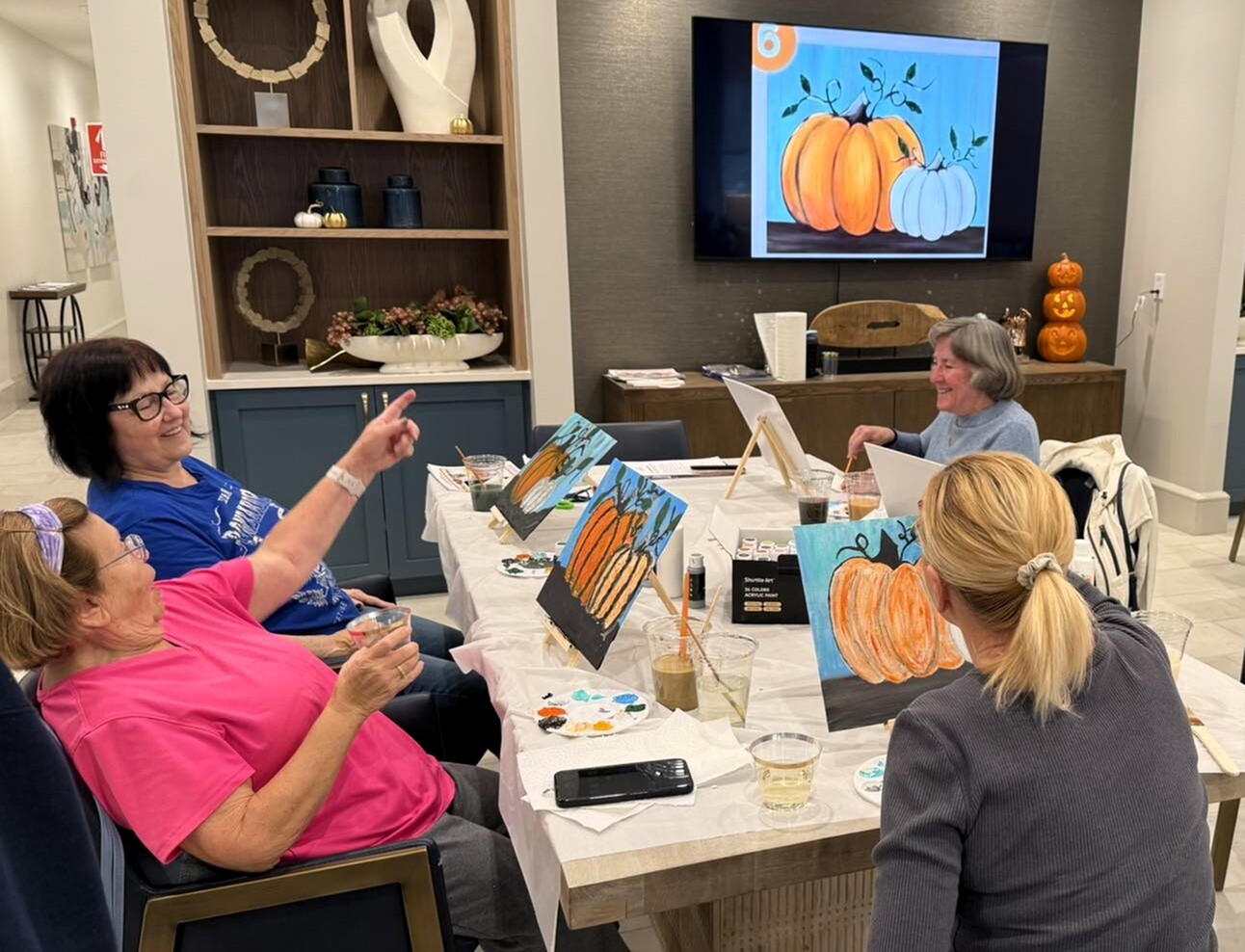 Residents enjoying a guided painting class with pumpkin artwork