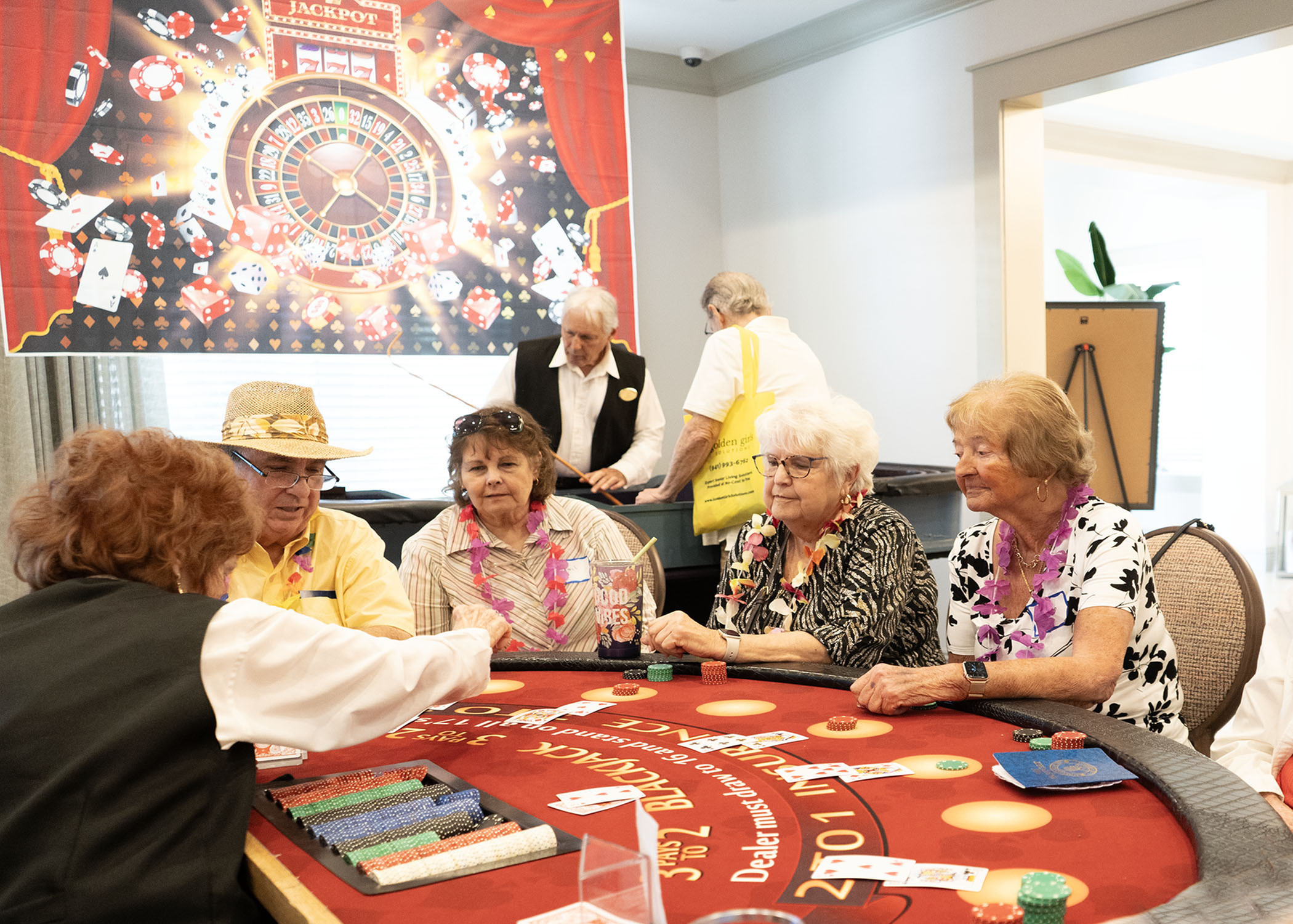 Residents gathered around a poker table playing poker in the Alloro at University Groves clubhouse at a social event