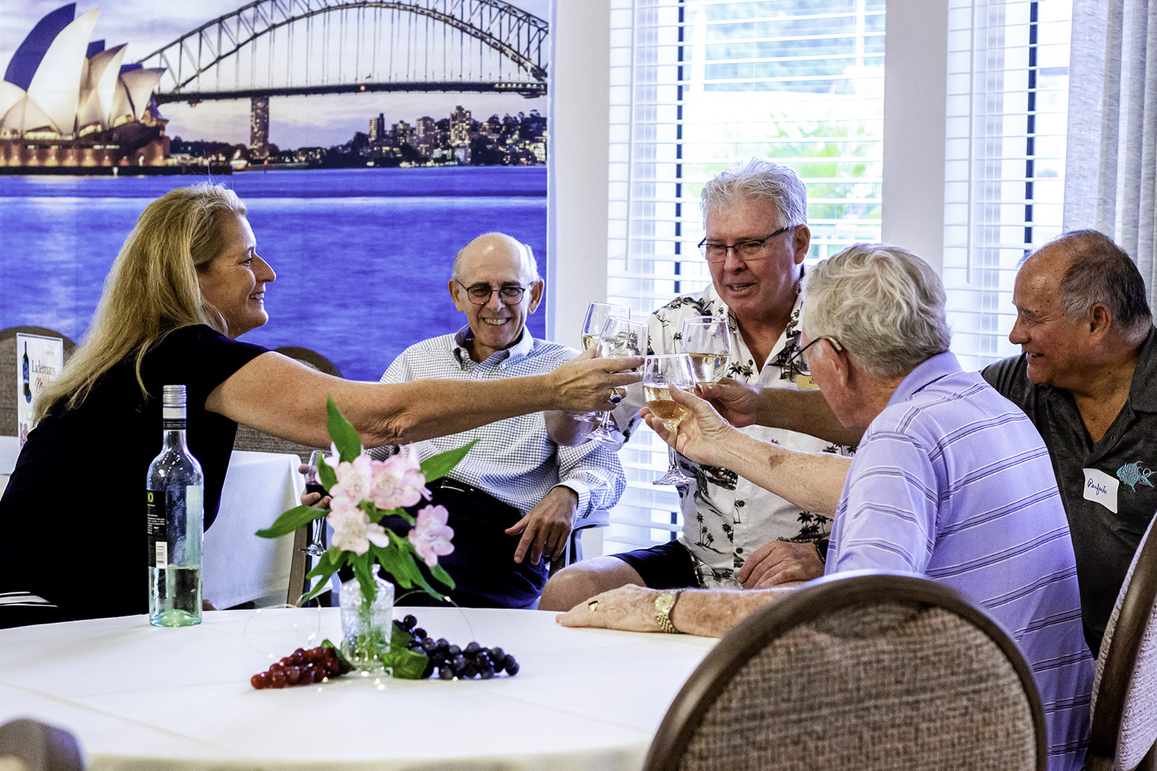 Group of Alloro residents smiling together and toasting their drinks during a social gathering