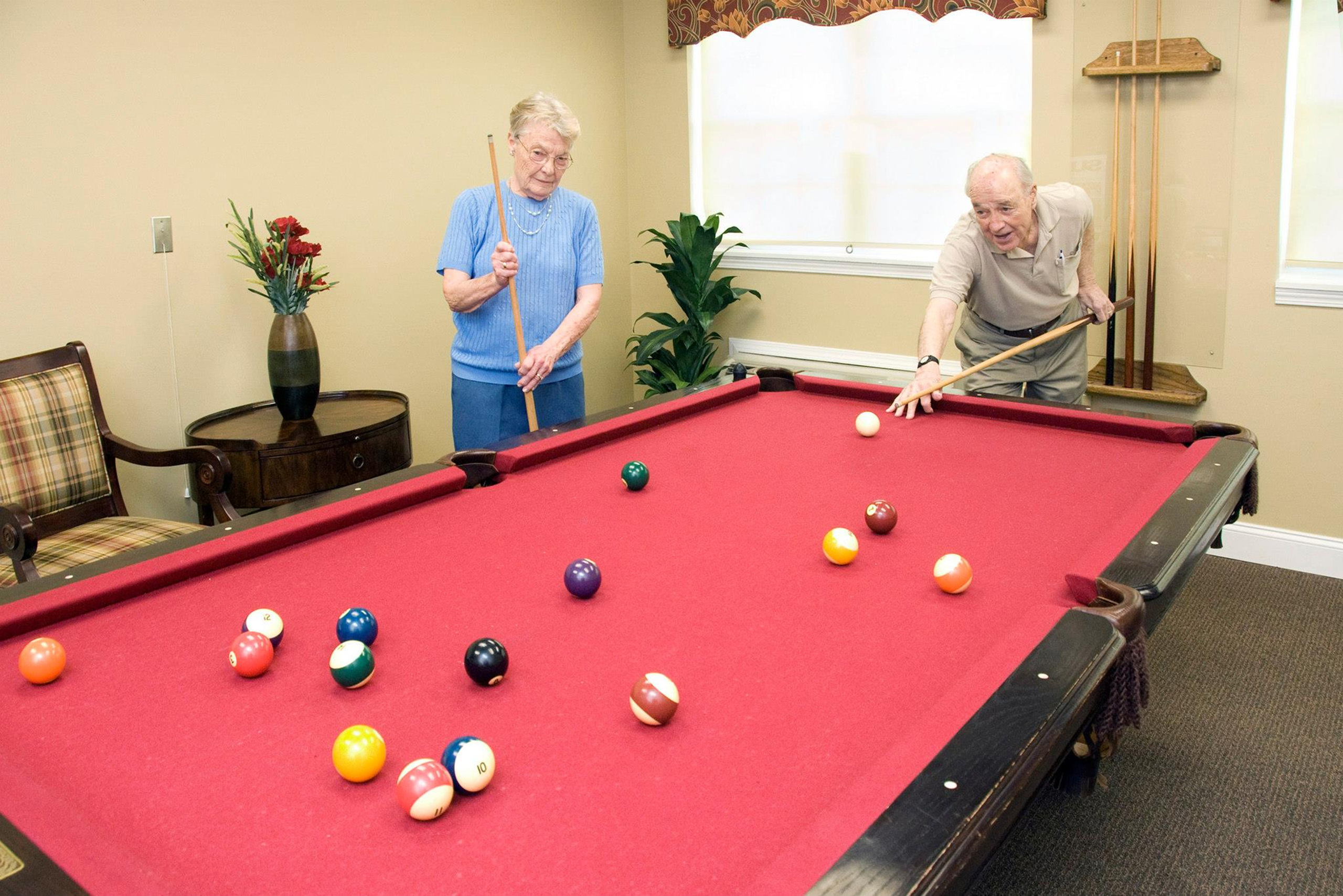 Two residents enjoying a game of billiards at Hearthstone Village