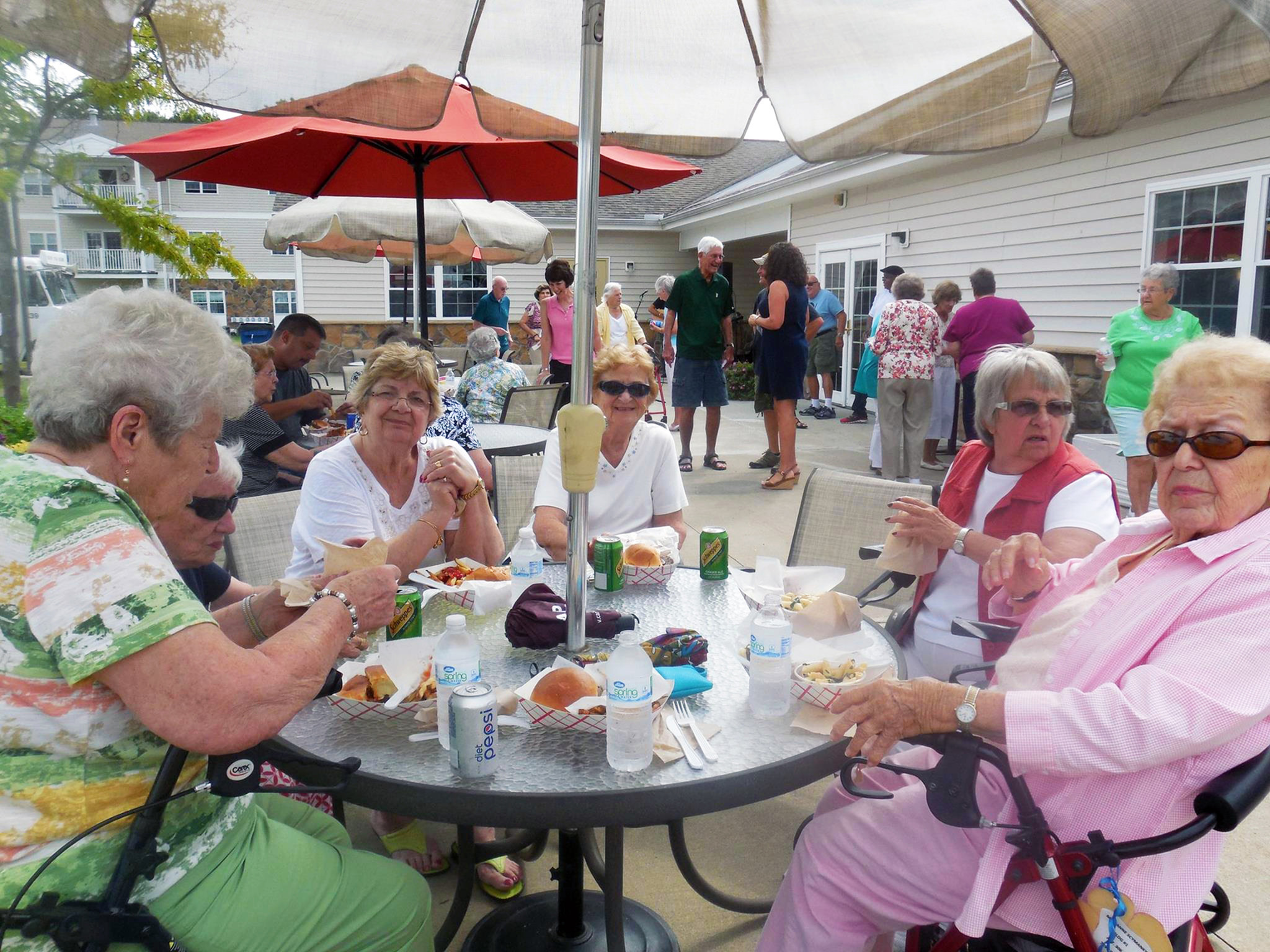 Residents gathered together sitting at a table outside, enjoying the sunny weather