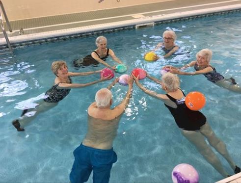 A group of residents swimming together in Hearthstone Village's indoor pool