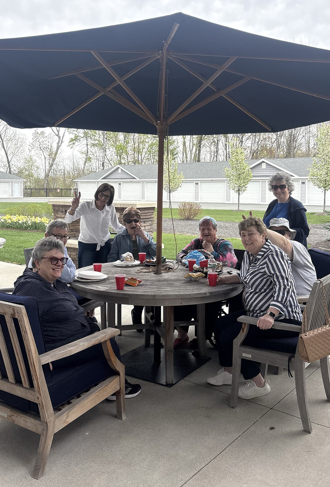 Residents sitting at a table outside, smiling at the camera