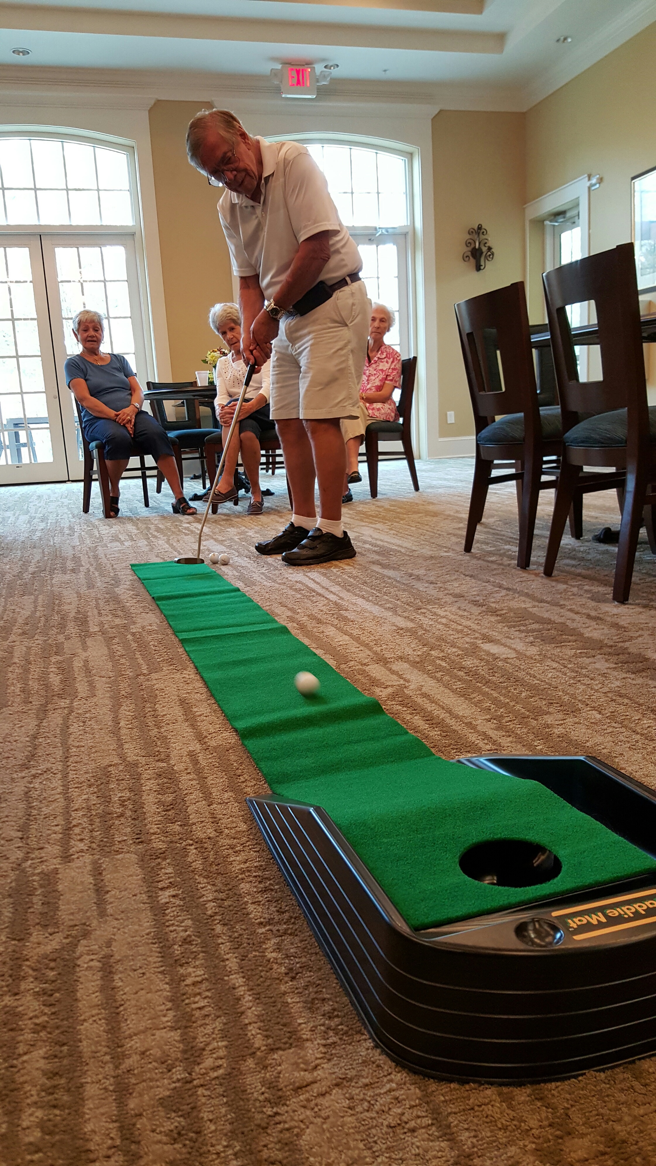 Sandalwood Village resident having fun while putting on a putting machine