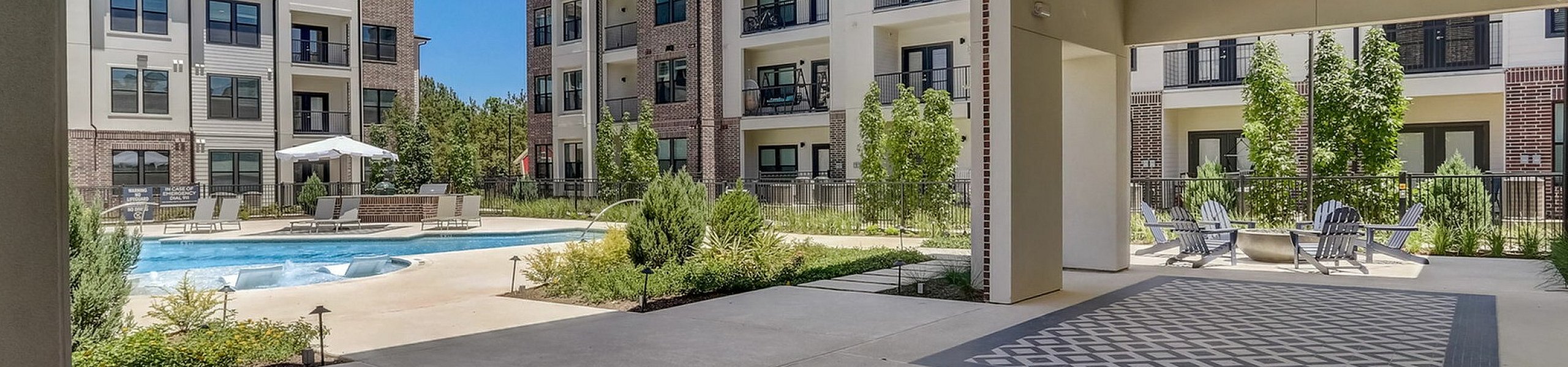 Chic outdoor area of a modern apartment complex with a pool and stylish seating.