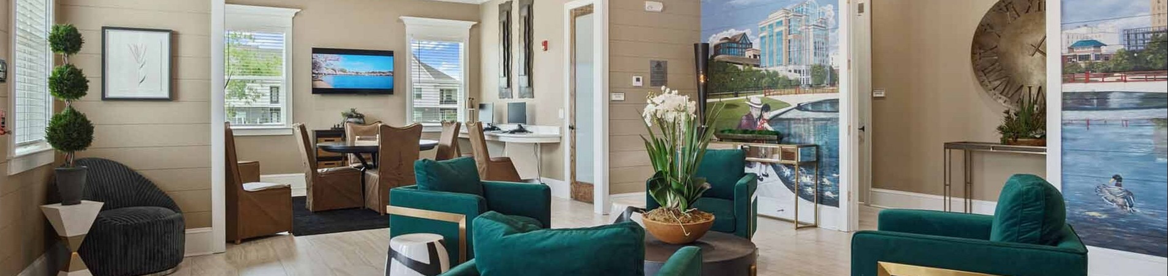 Elegant living space featuring modern green armchairs, large mural wall, stylish chandelier, and natural light.