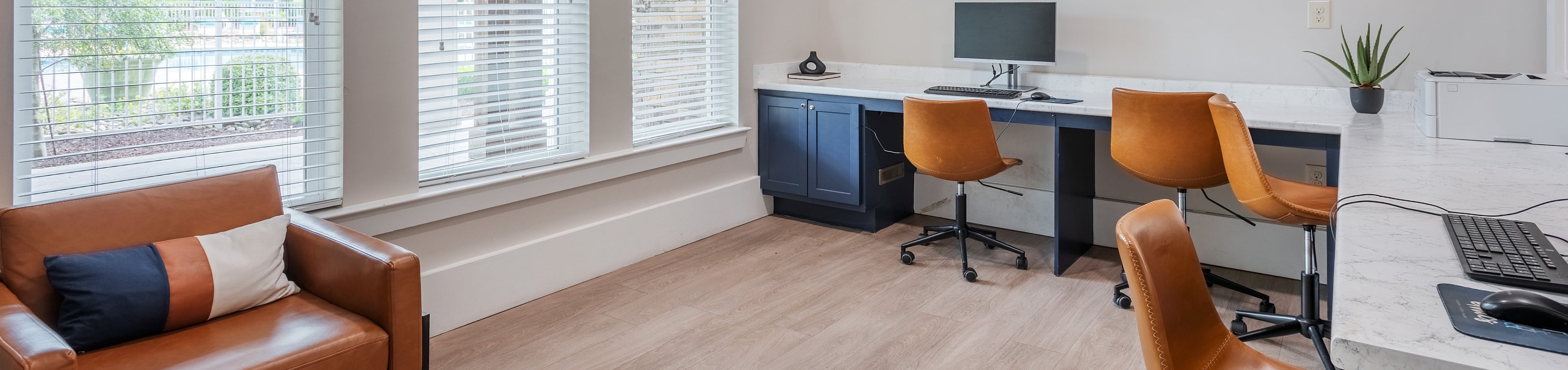 Bright and modern workspace featuring stylish leather chairs, white marble countertops, and ample natural light through large windows.