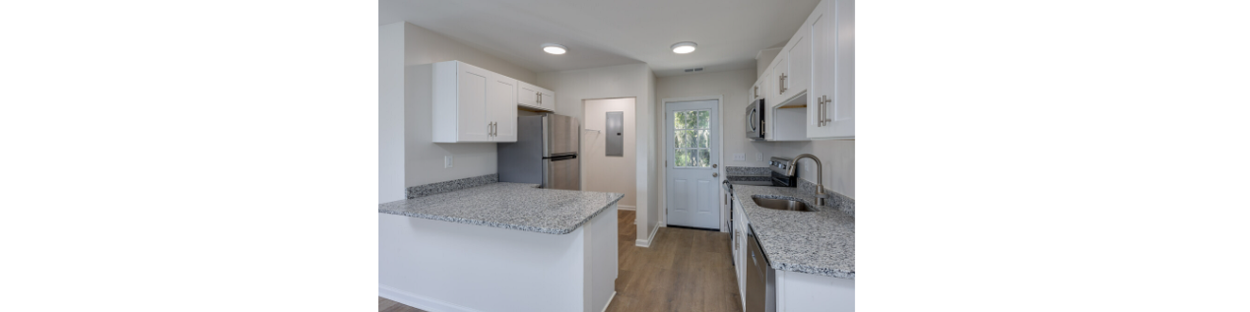 Sleek kitchen area featuring granite countertops, stainless steel appliances, and white cabinetry.