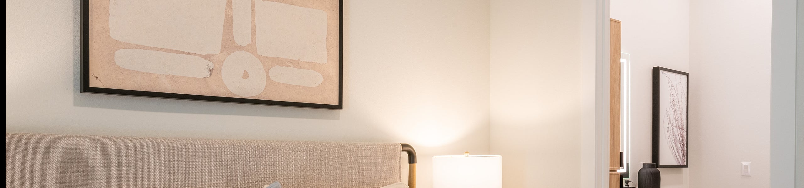 Elegant bedroom with plush bedding, warm lighting, and an ensuite bathroom showcasing modern decor.