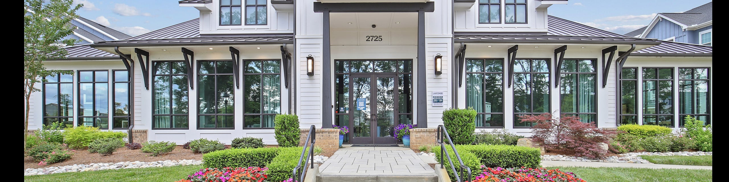 Charming modern building facade with large windows and vibrant flower garden, exuding elegance and tranquility.