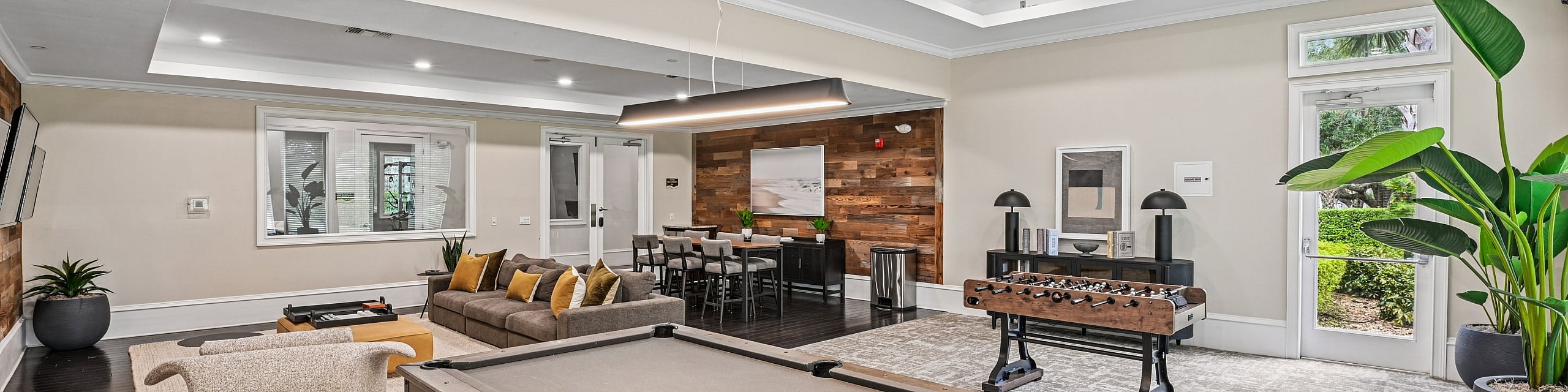 Luxurious recreational room featuring a stylish pool table, cozy seating area with plush sofas, foosball table, and elegant wood accents, perfect for relaxation and entertainment.