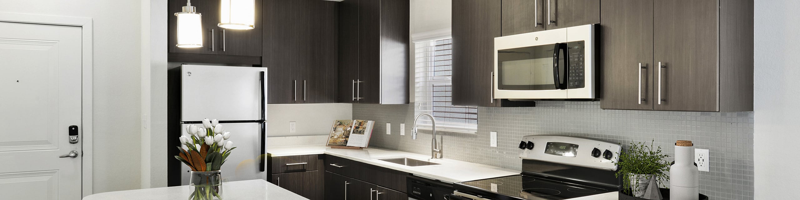 Modern kitchen with sleek dark cabinetry, stainless steel appliances, and a stylish white quartz countertop island with pendant lighting and comfortable seating.