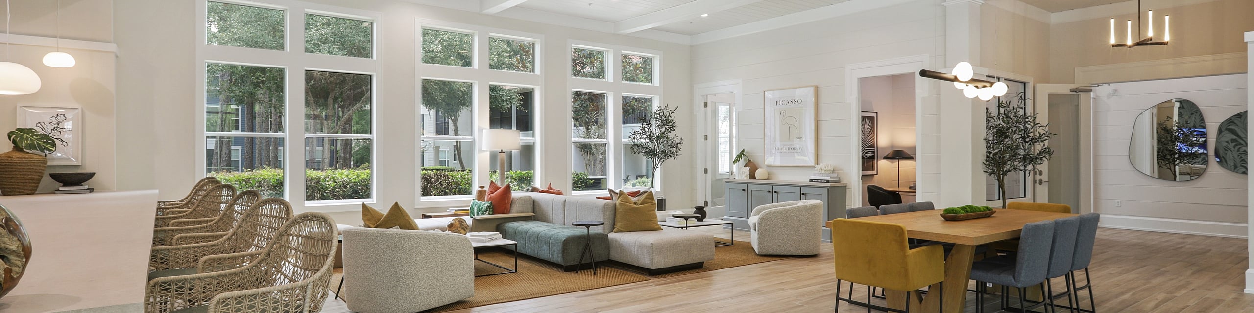 Bright, spacious living area with modern decor and large windows offering garden views; features cozy seating, elegant dining table, and stylish bar stools.