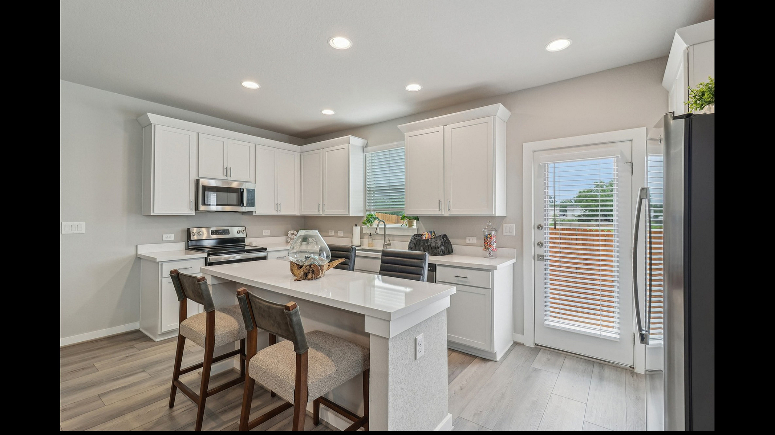 Bright and modern kitchen featuring sleek white cabinetry, stainless steel appliances, and a stylish island with seating.