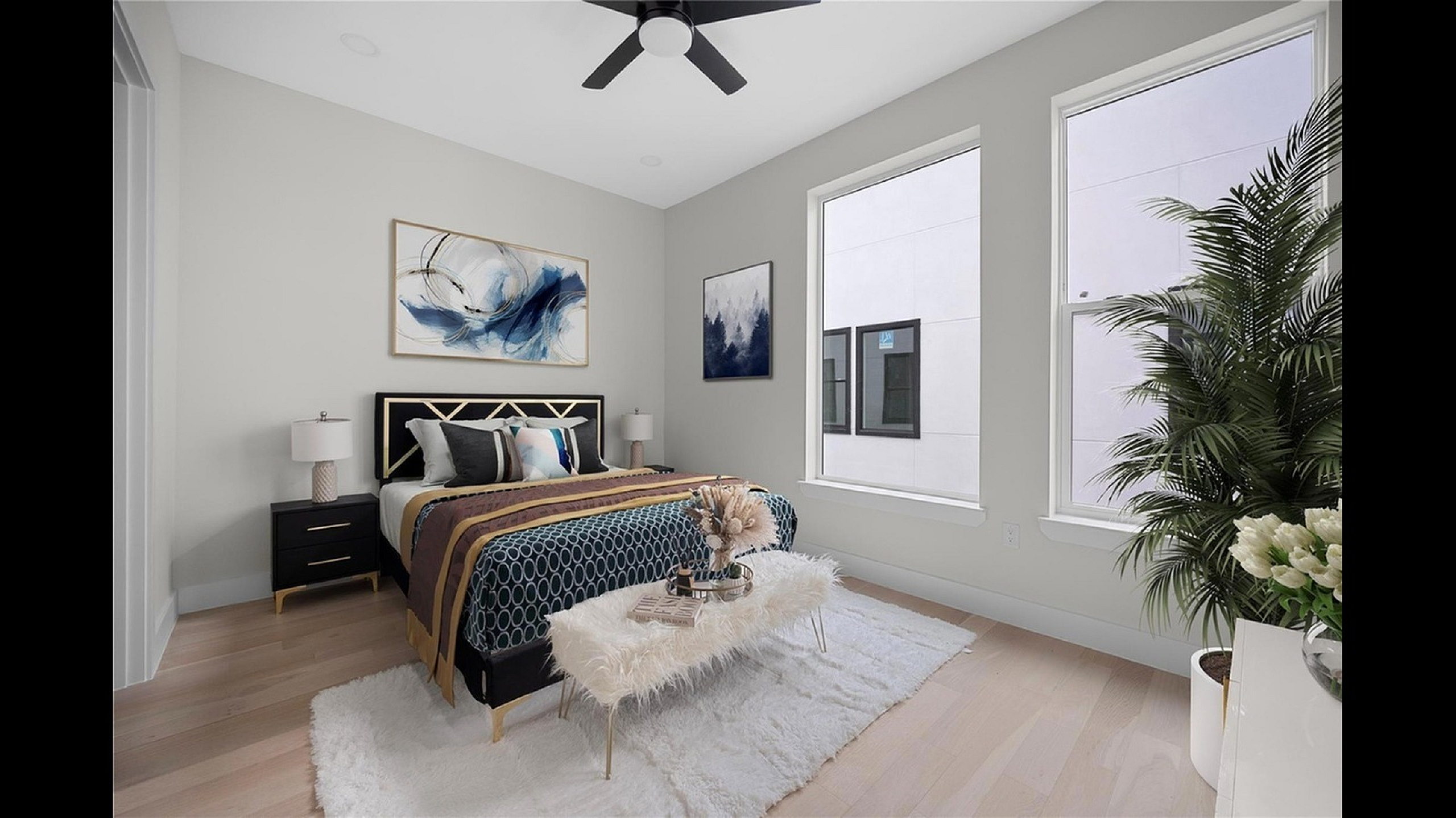 Elegant bedroom with modern decor, featuring a plush bed, abstract artwork, and large windows flooding the room with natural light.