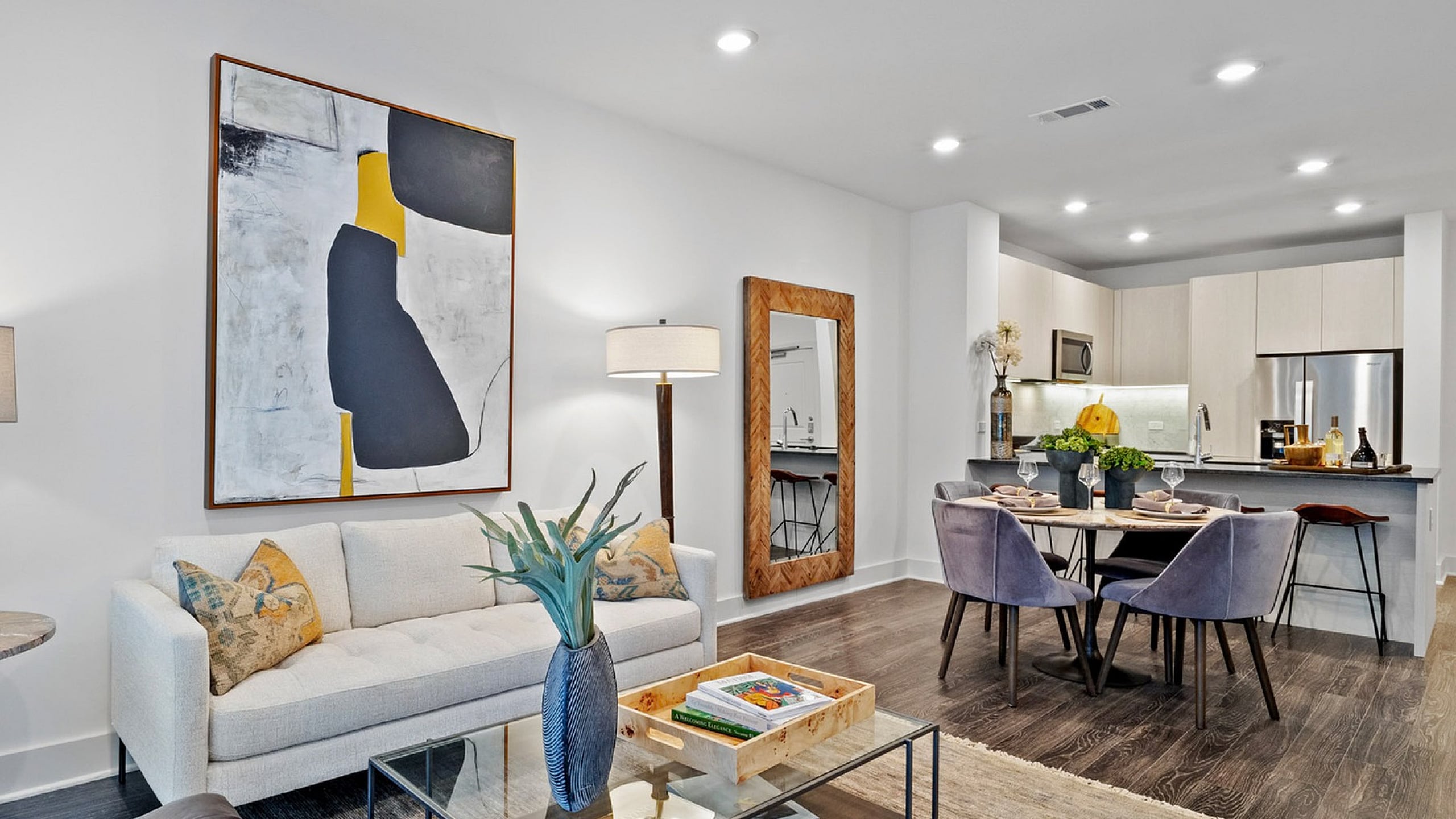 Modern open-concept living space featuring a chic living room, dining area, and stylish kitchen with elegant decor and contemporary artwork.