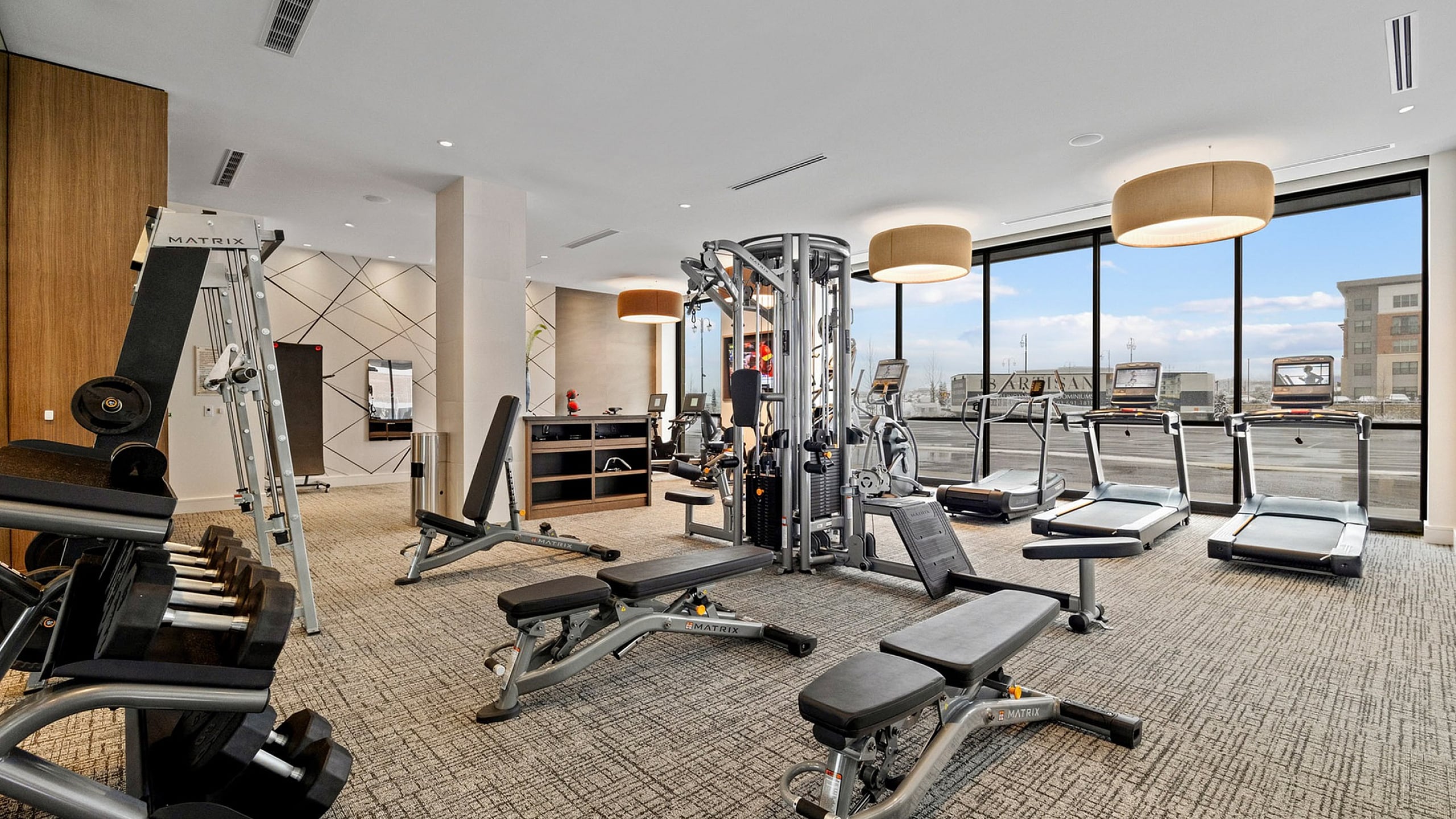 Modern fitness center with state-of-the-art equipment, including treadmills, weight machines, and free weights, set in a bright, spacious environment with large windows.