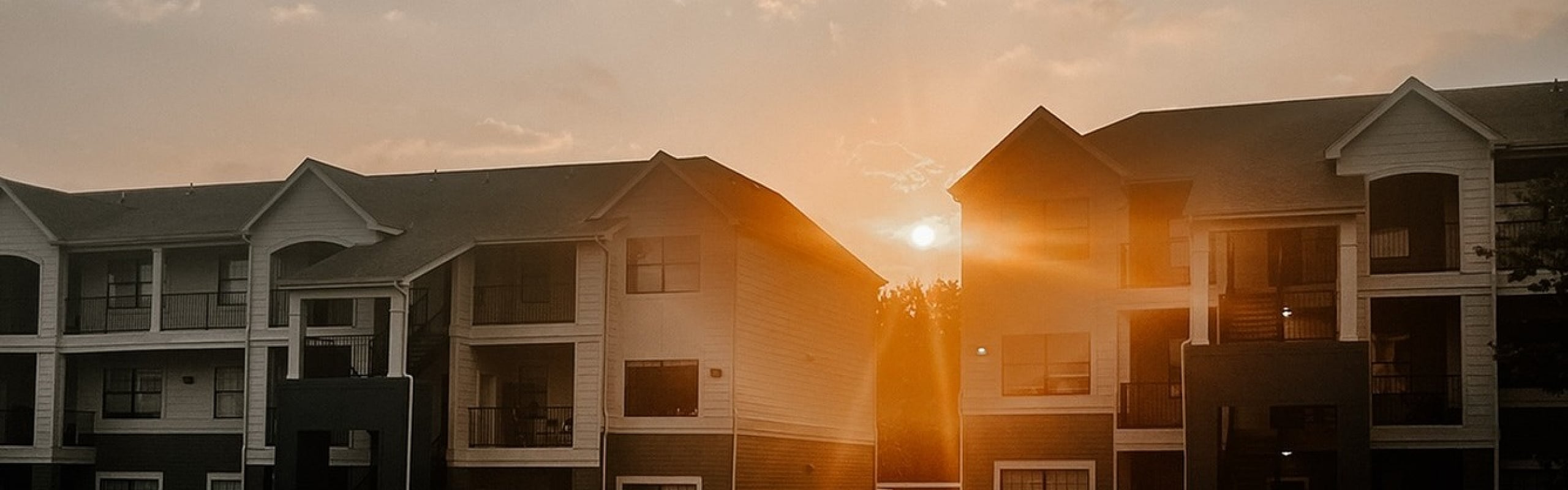 Charming apartment buildings at sunset, with a warm glow highlighting the inviting exterior and serene surroundings.