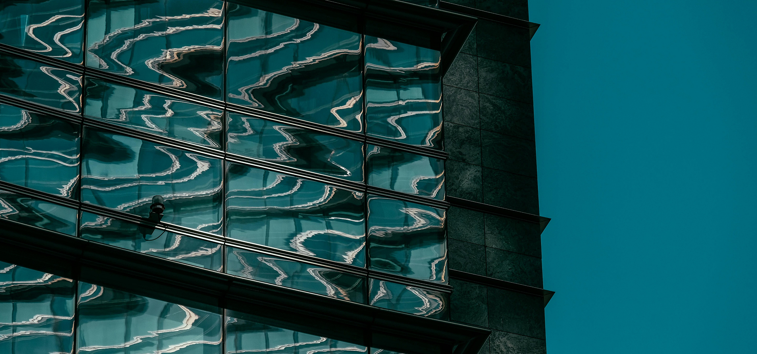 Contemporary glass building facade with artistic reflections of sky and clouds, offering a modern and stylish urban aesthetic.