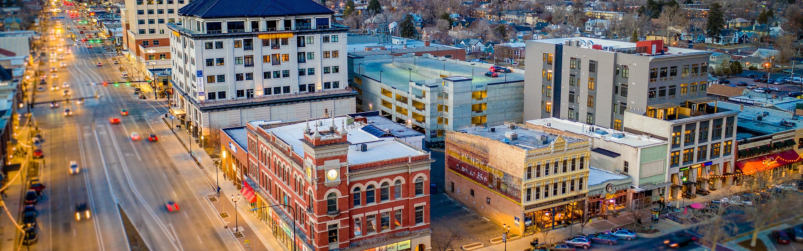 Vibrant aerial view of a city street with tall modern buildings and bustling nightlife.