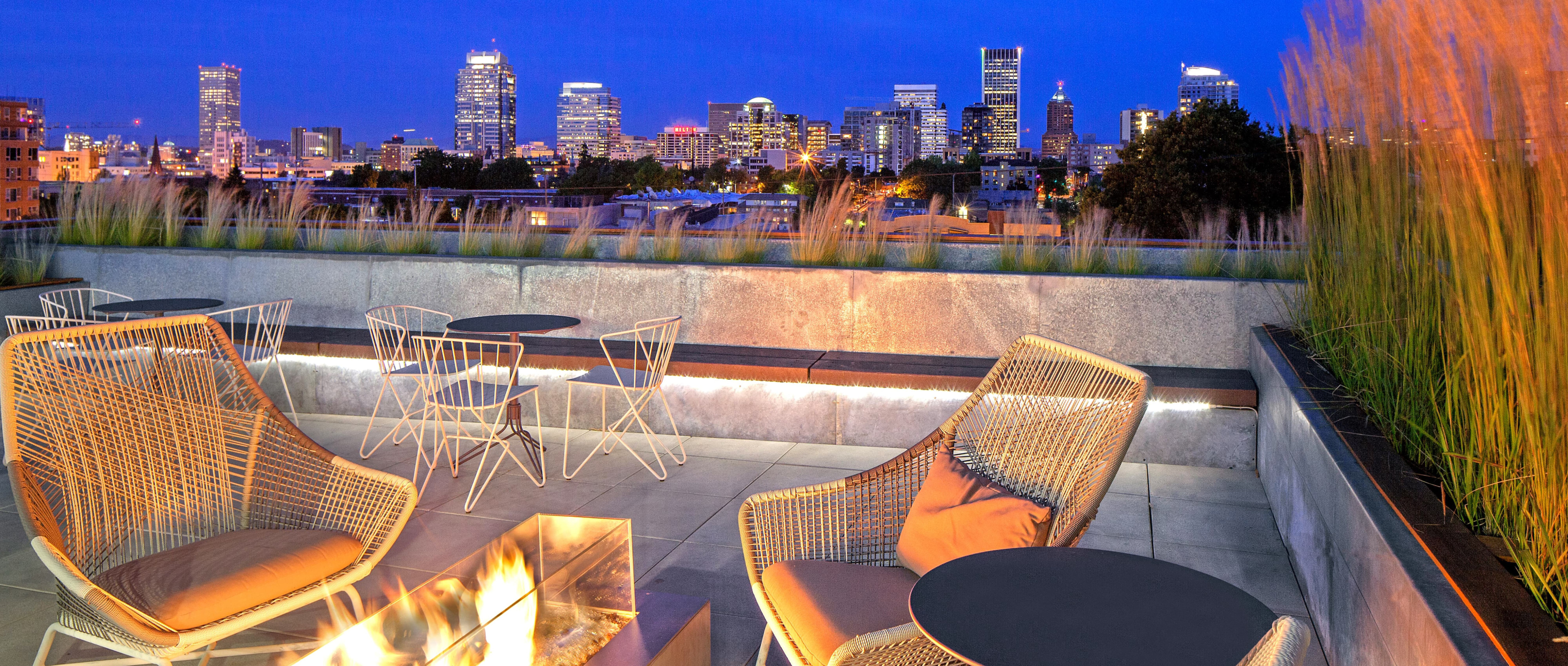 Tanner Flat Flats Apartments roof top patio with fire place and chairs and view of downtown Portland