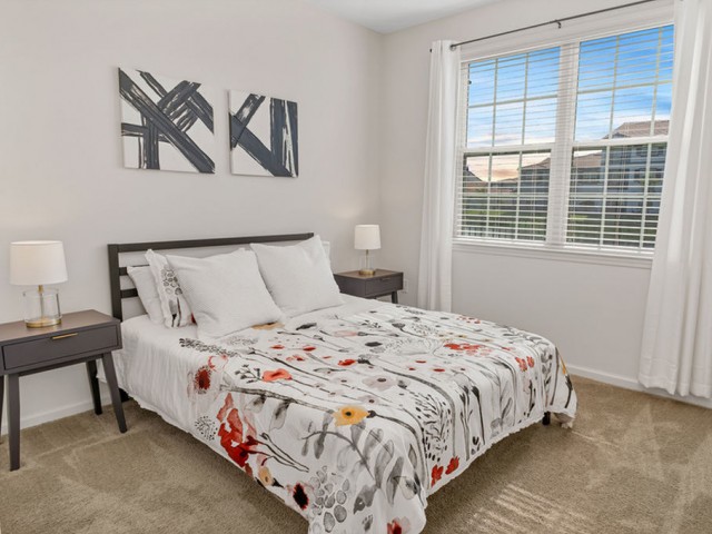 Venetian Apartments Ft. Myers guest bedroom with queen size bed and end tables, plush carpet and double window.