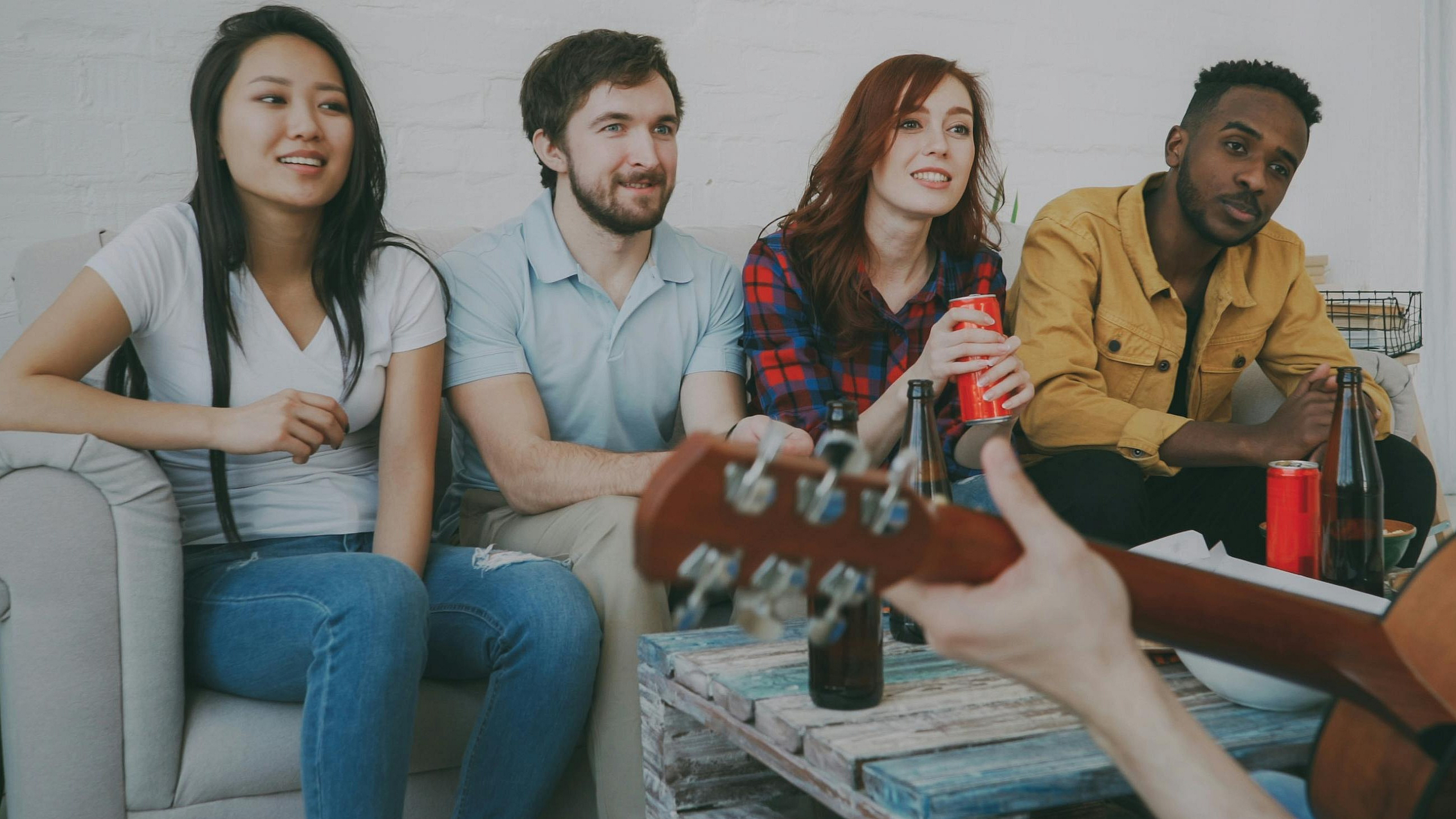 young-friends-enjoying-guitar-music-indoors