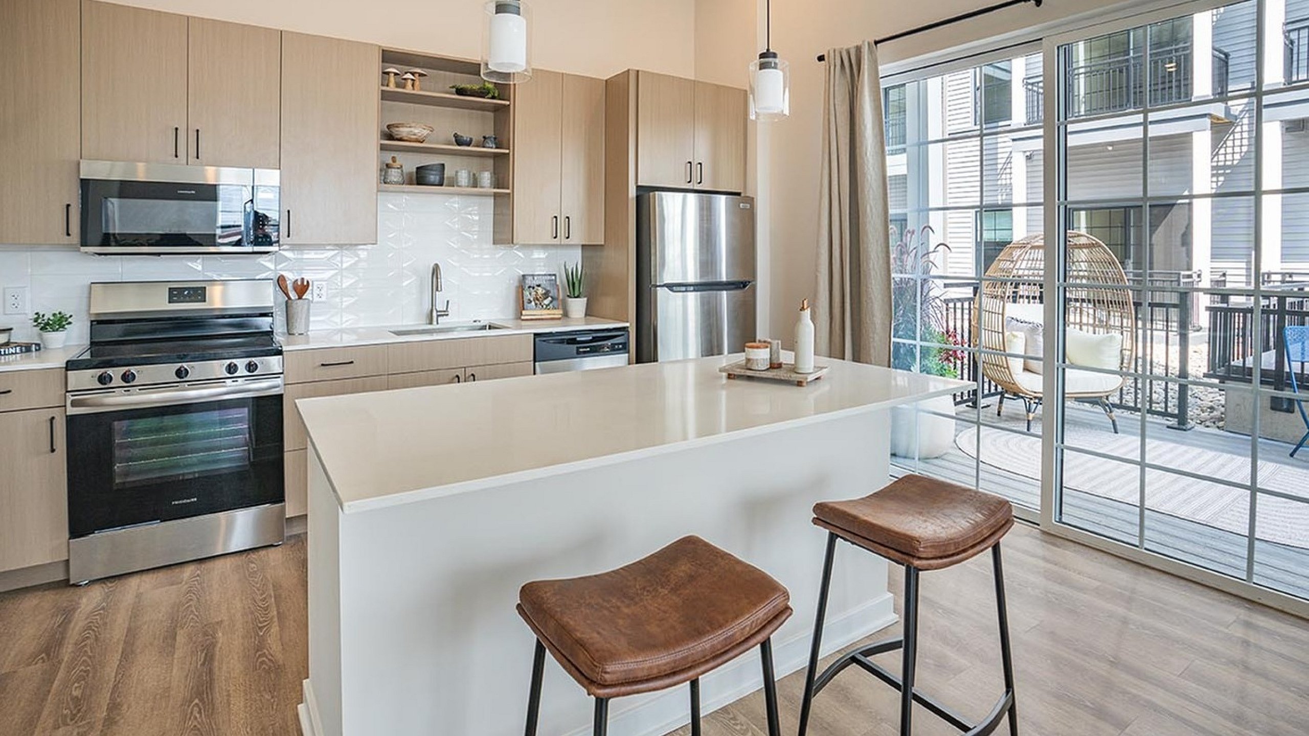 Bright modern kitchen with sleek cabinetry, center island, and outdoor view.