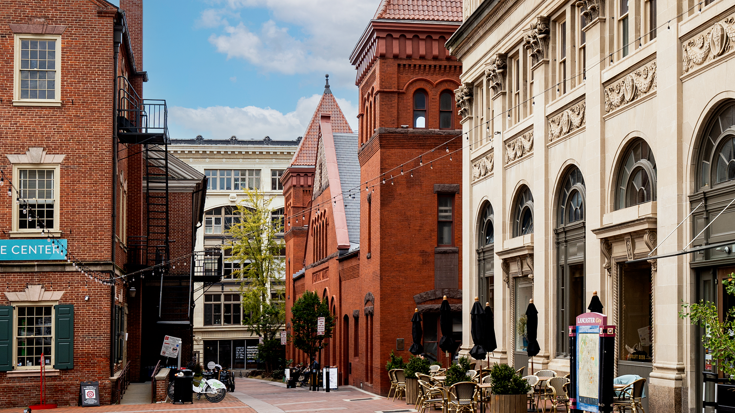 Charming urban street view featuring historic brick buildings and elegant outdoor seating, perfect for city living.