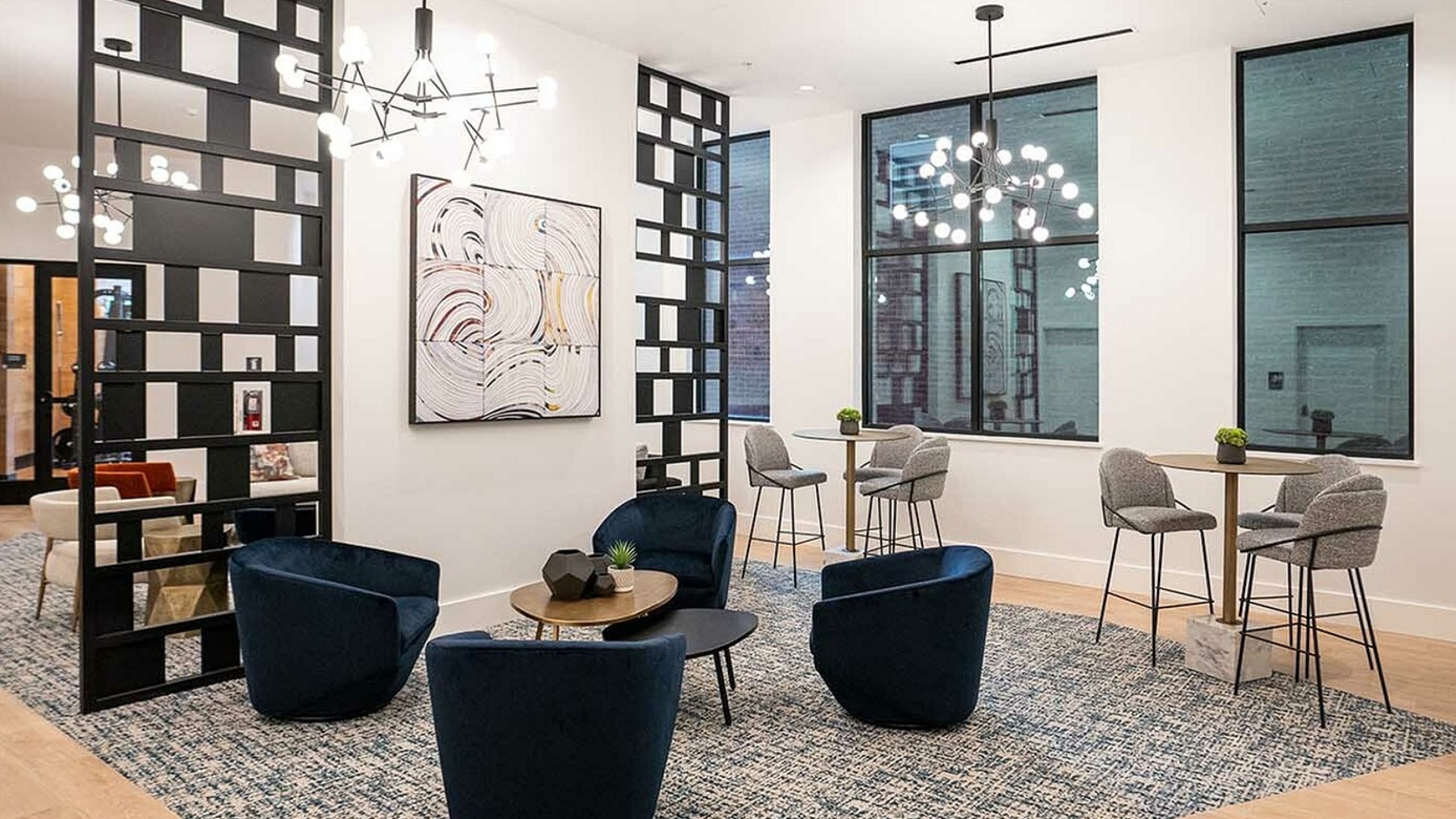Contemporary seating area with chic blue velvet chairs and stylish lighting in a modern, open lounge space.