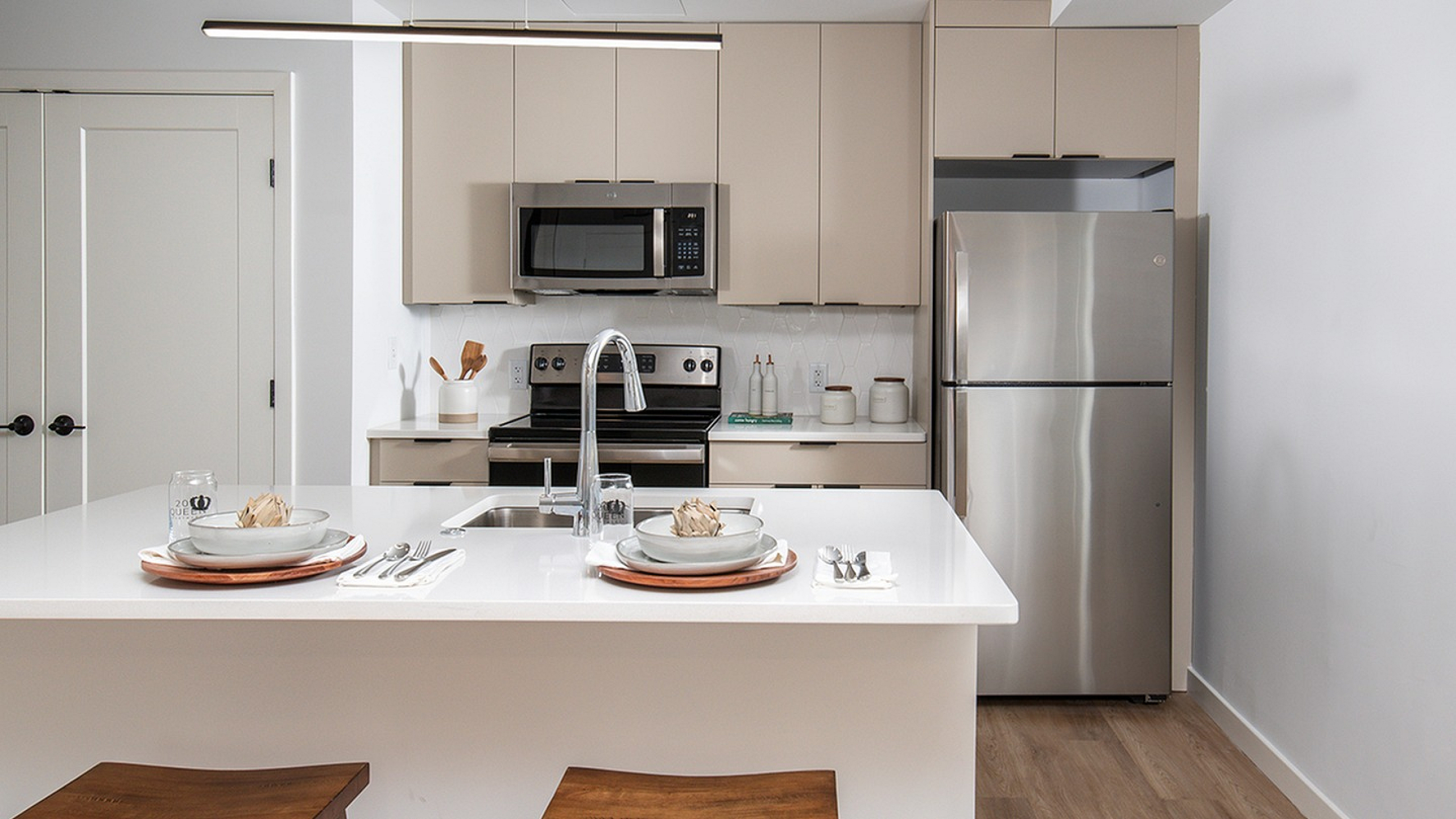 Sleek modern kitchen featuring a stylish island with elegant dining setup, stainless steel appliances, and warm wooden accents.