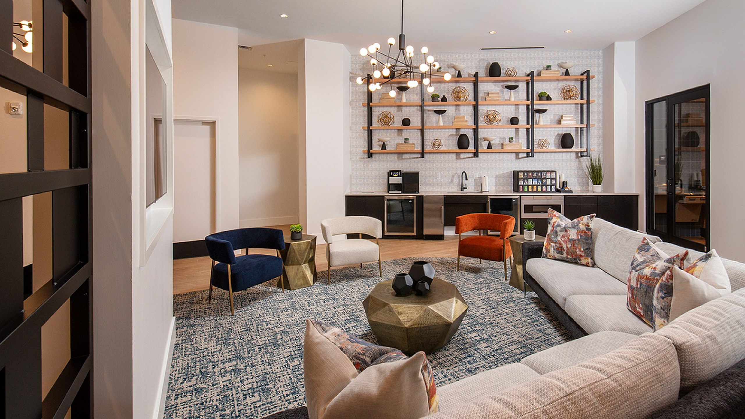 Modern living area with elegant decor, featuring a cozy L-shaped sofa, vibrant accent chairs, stylish bookshelf, and a chic geometric coffee table under contemporary lighting.