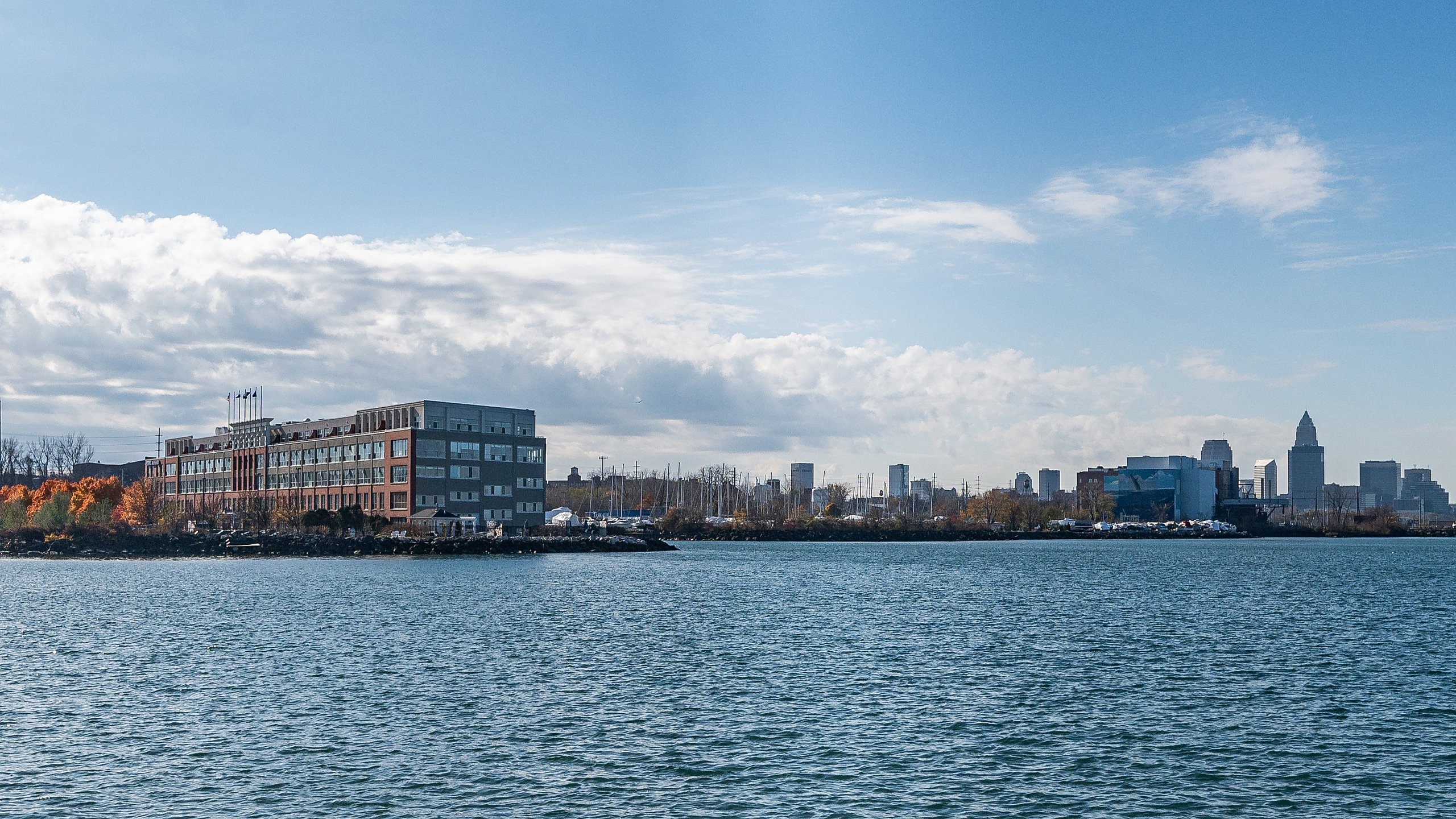Charming waterfront view with a stylish apartment building and city skyline, showcasing vibrant autumn colors.