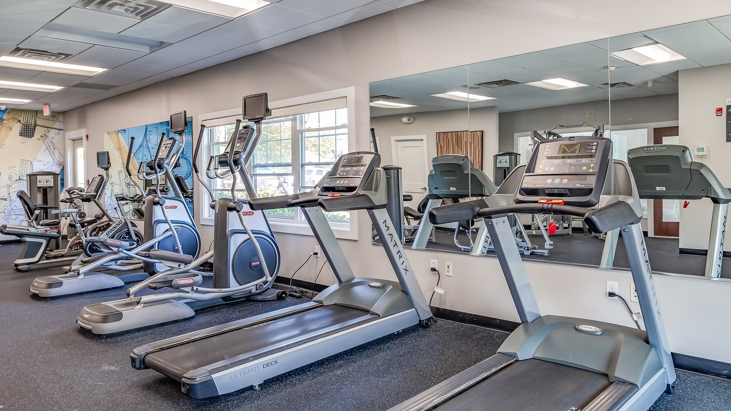 Bright and modern fitness center featuring state-of-the-art treadmills and exercise bikes with wall-to-wall mirrors, ideal for a healthy lifestyle.