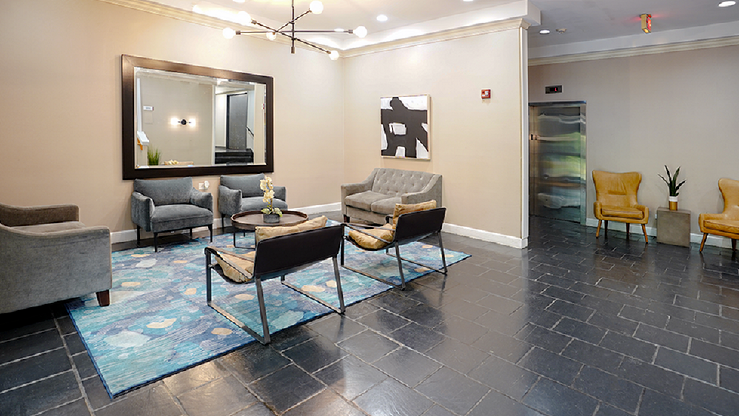 Inviting lobby area featuring elegant seating, modern lighting, and a chic blue rug, offering a warm and stylish welcome.