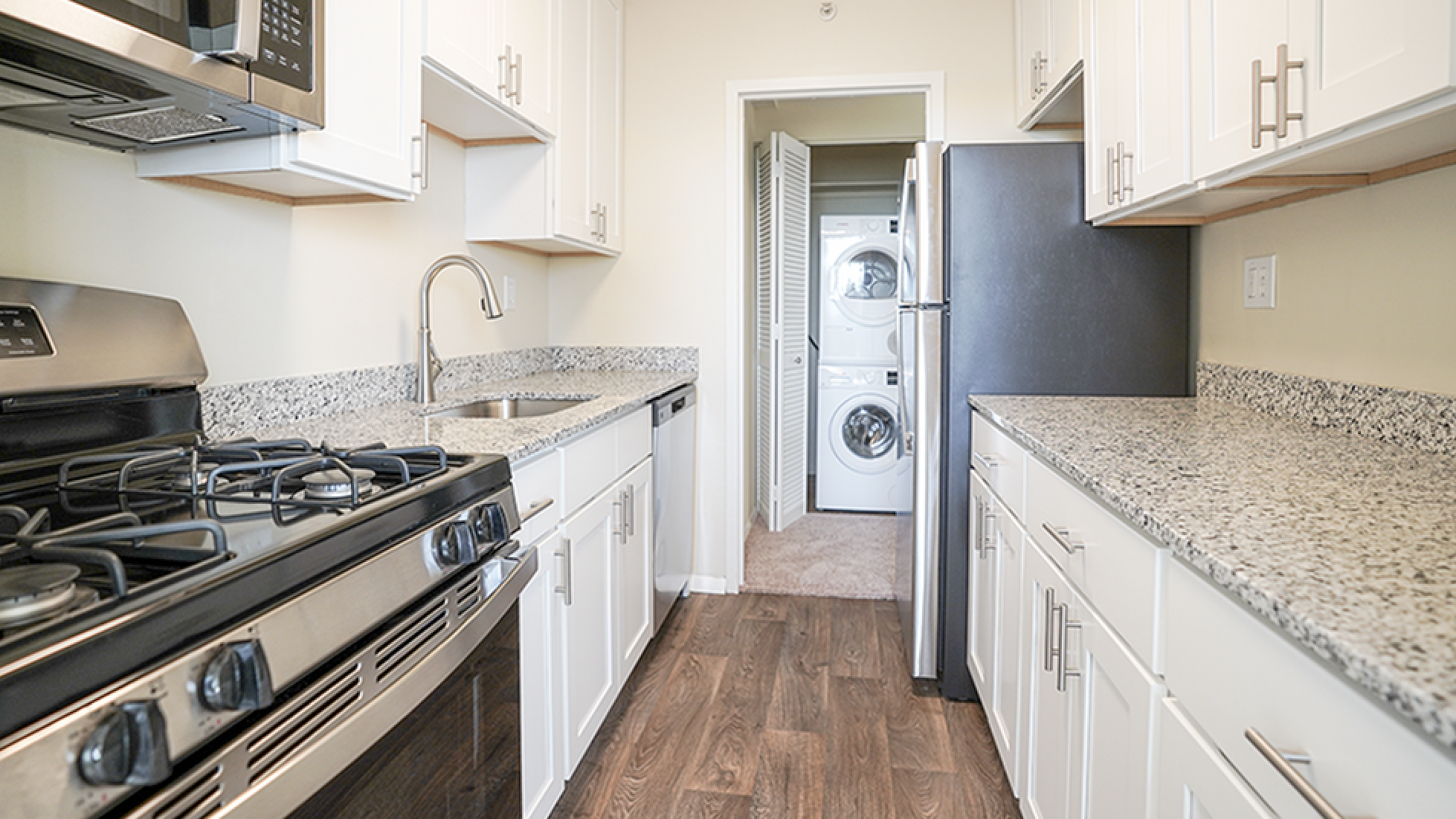 Modern kitchen with sleek granite countertops, stainless steel appliances, and in-unit laundry for convenience.