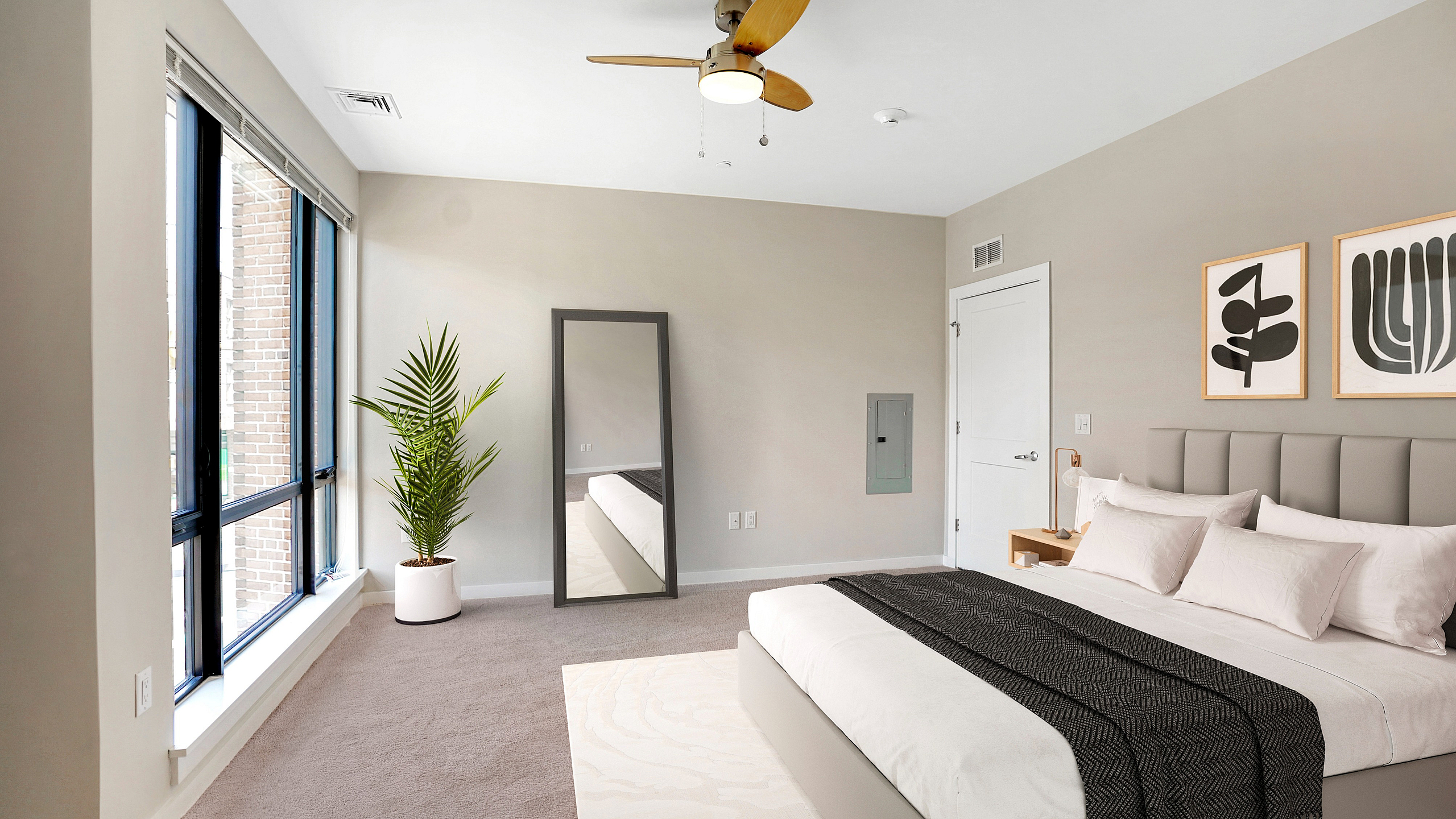 Bright and inviting bedroom with modern decor, large windows, and elegant ceiling fan, perfect for a cozy retreat.