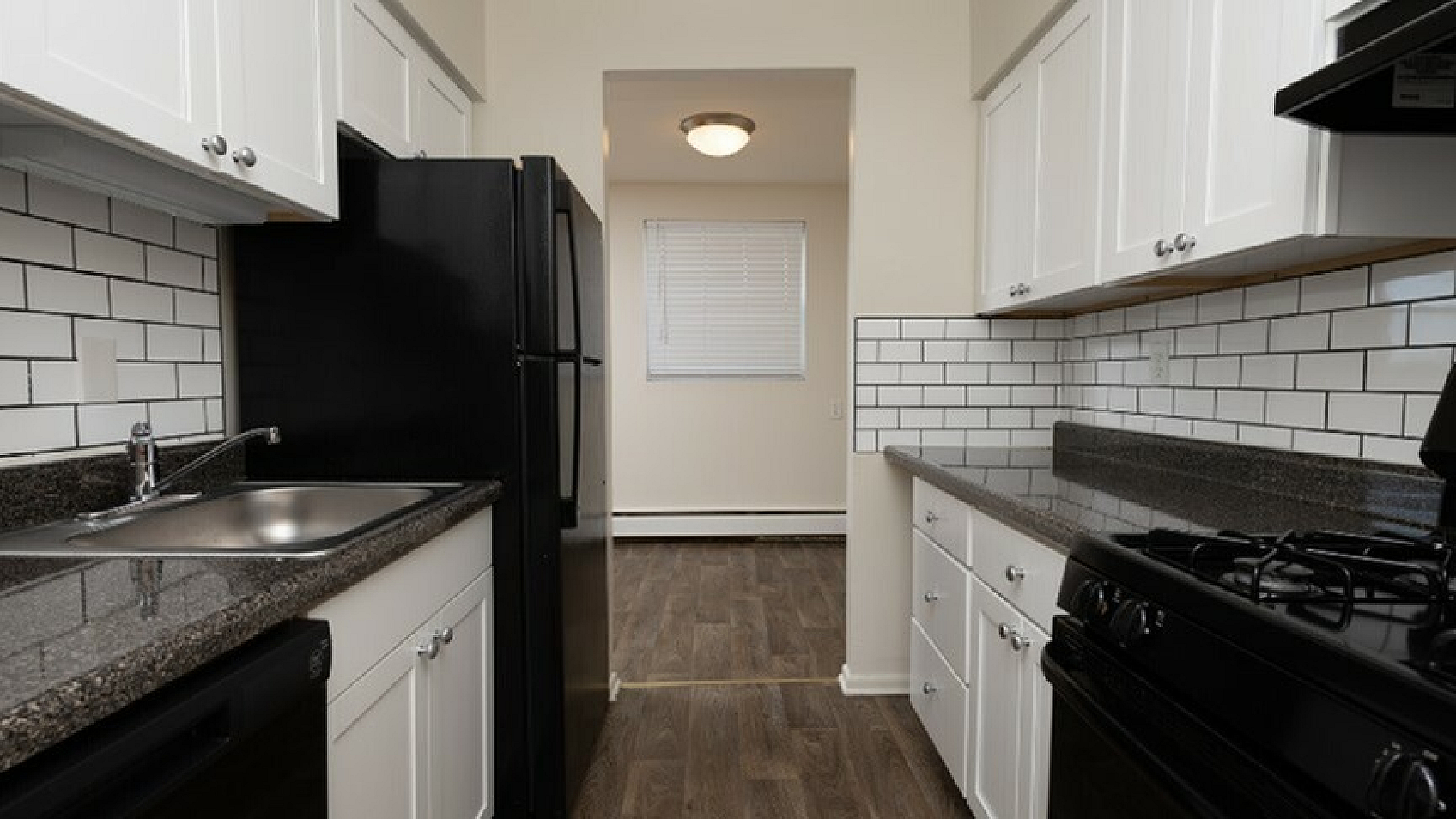 Modern kitchen with sleek black appliances, elegant white cabinetry, and stylish subway tile backsplash.