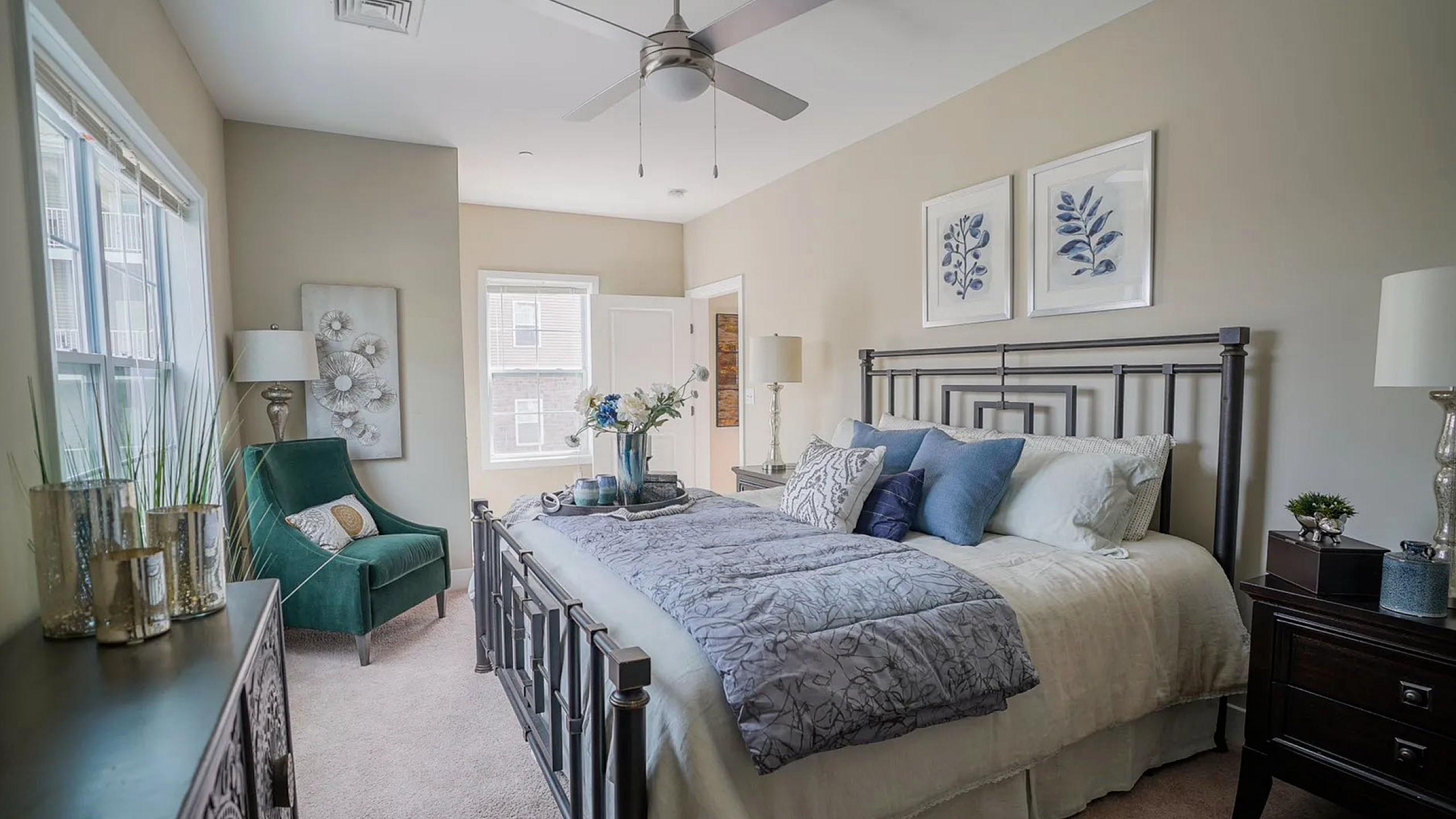 Elegant bedroom with modern decor, featuring a cozy bed with plush pillows, a stylish green chair, and tasteful artwork, creating a serene and inviting atmosphere.