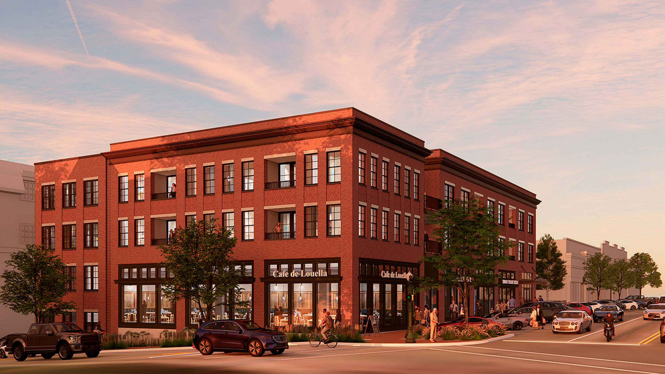 Elegant red-brick building with spacious balconies and large windows, housing a charming street-level caf&eacute;, set against a picturesque sunset.