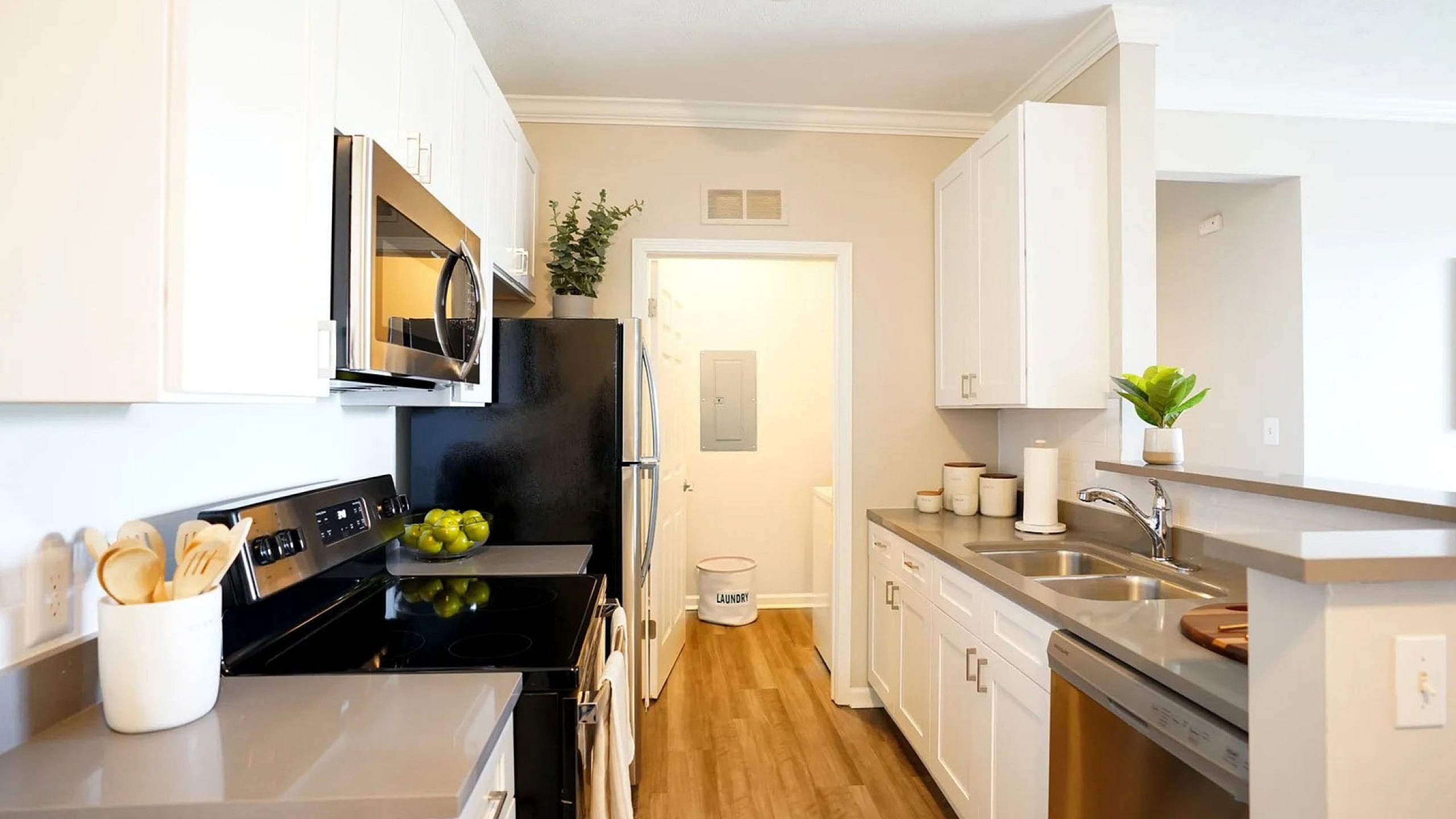 Chic modern kitchen with stainless steel appliances, elegant white cabinetry, and warm wood flooring, offering a bright and inviting cooking space.