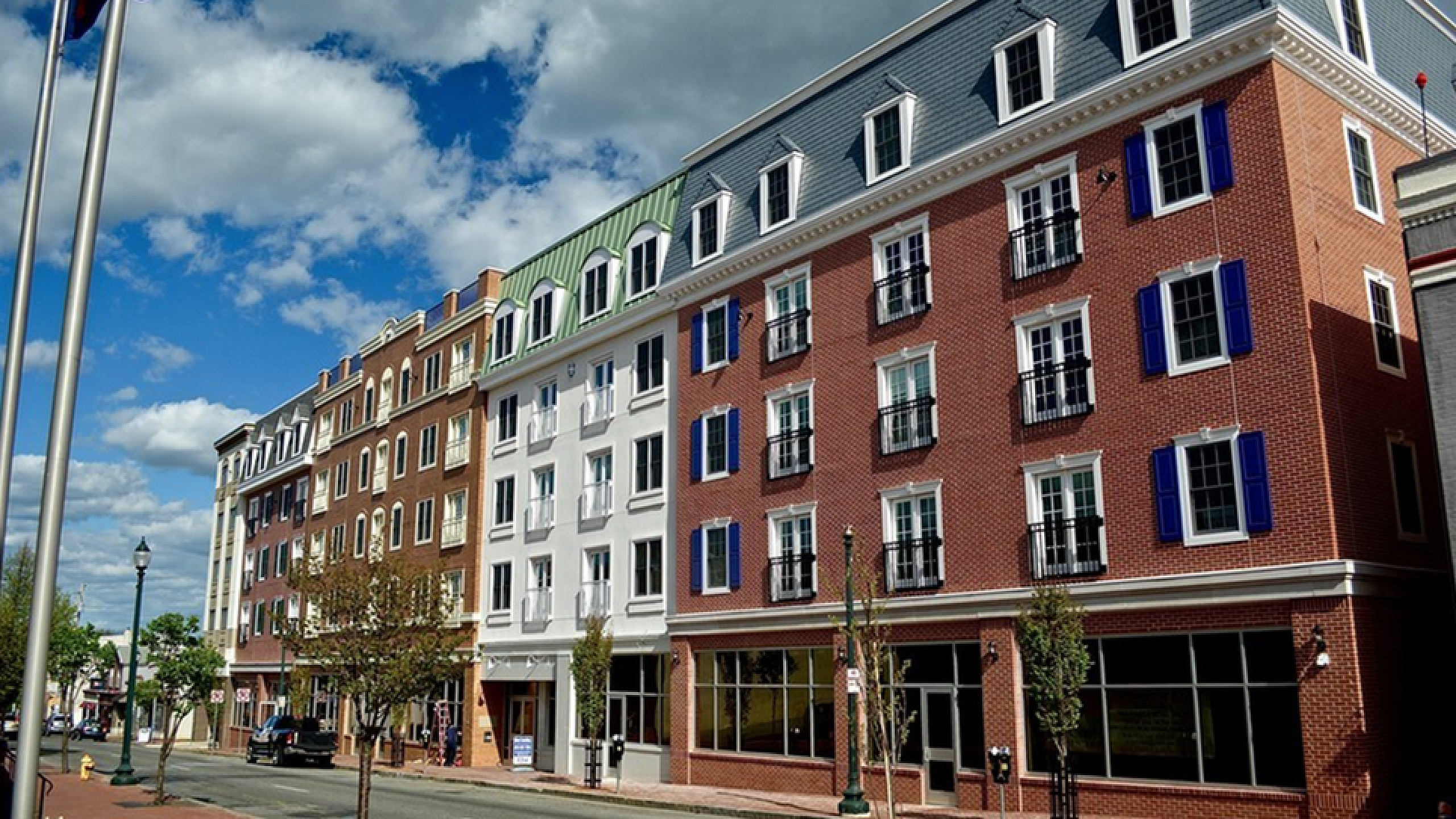 Charming urban apartment building with brick facade and elegant architecture, showcasing vibrant blue shutters against a sunny backdrop.