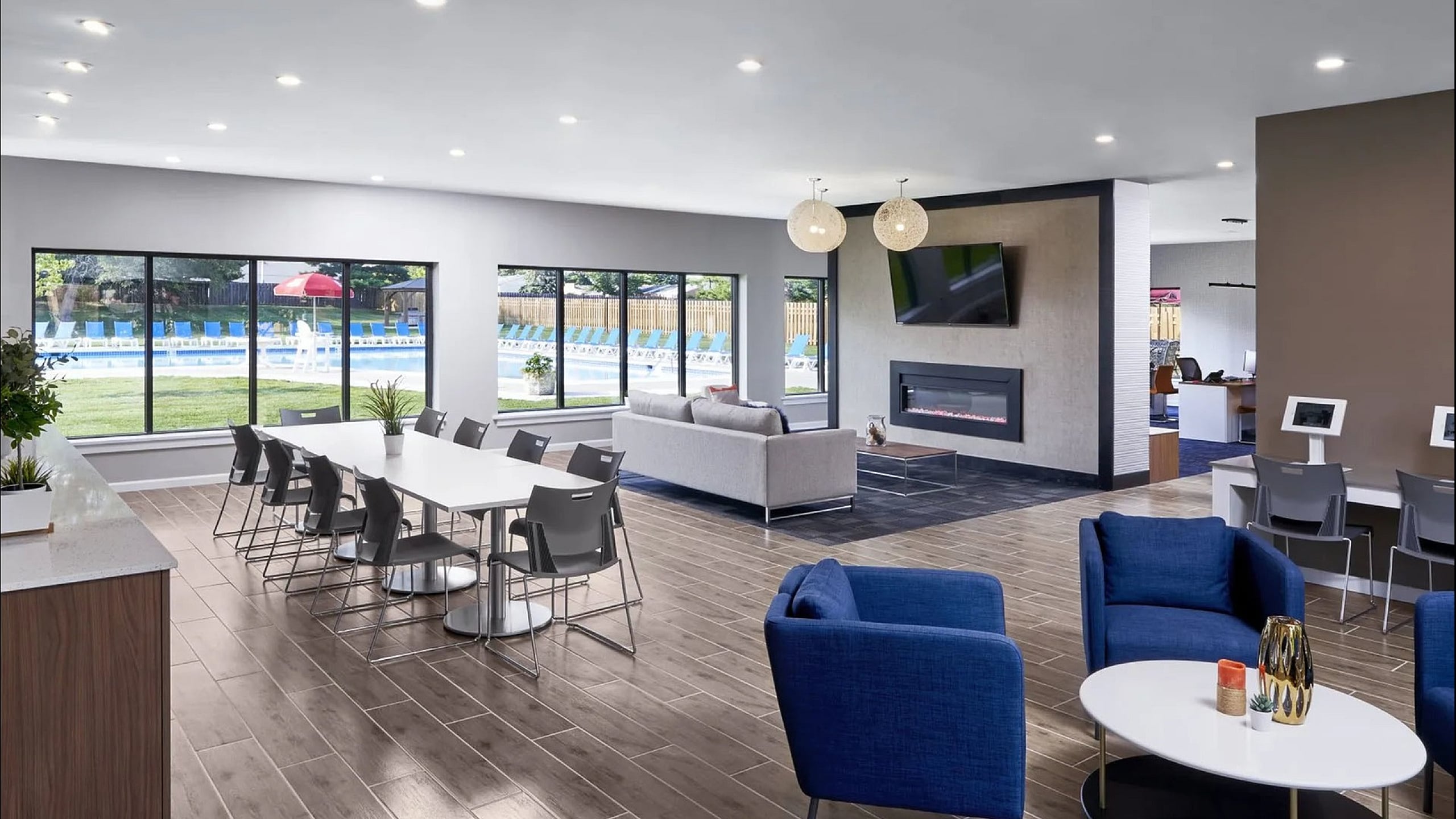 Modern communal area with sleek dining, comfortable seating, and large windows overlooking a scenic poolside.