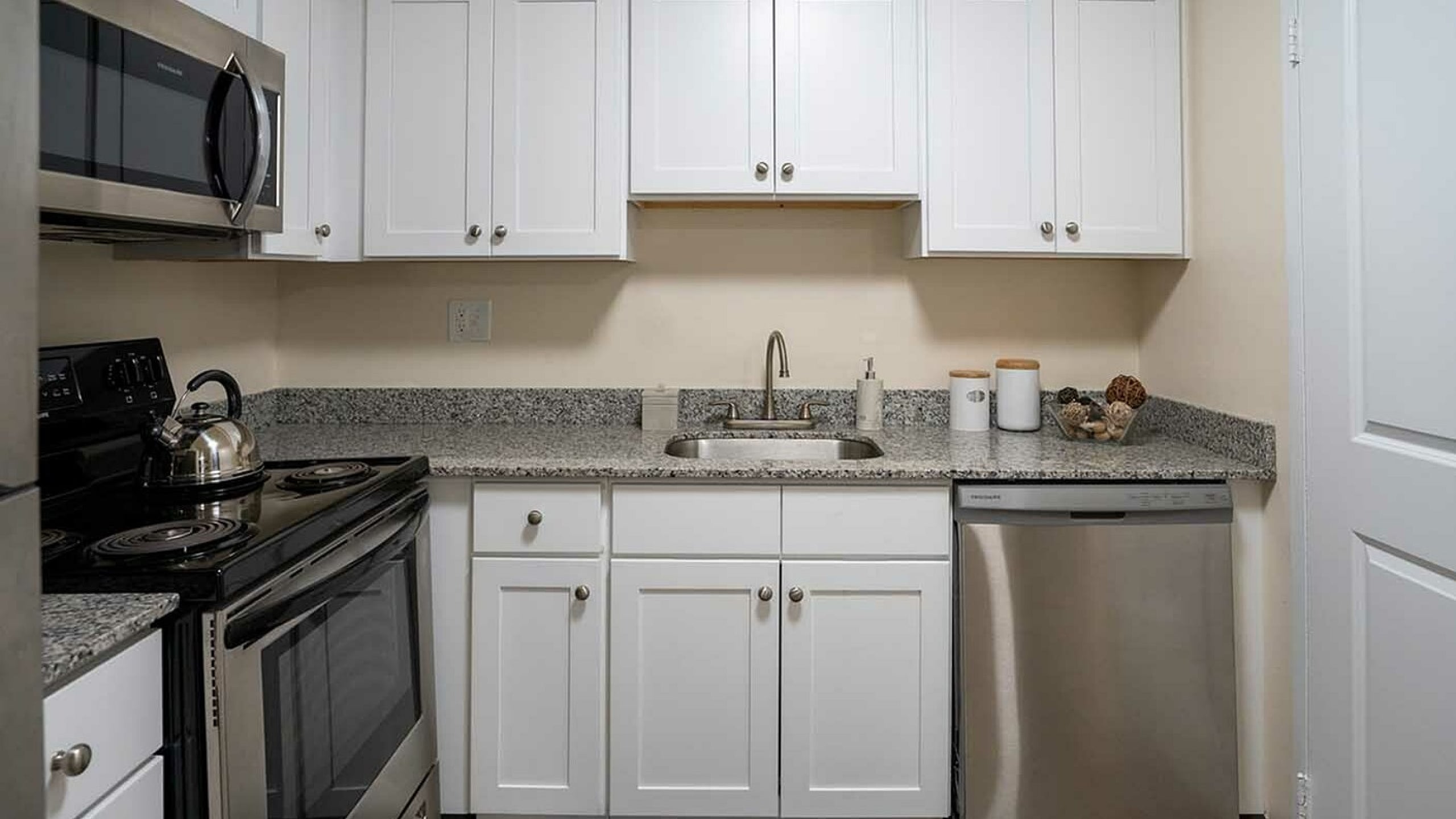 Modern kitchen with sleek stainless steel appliances, granite countertops, and stylish white cabinetry.