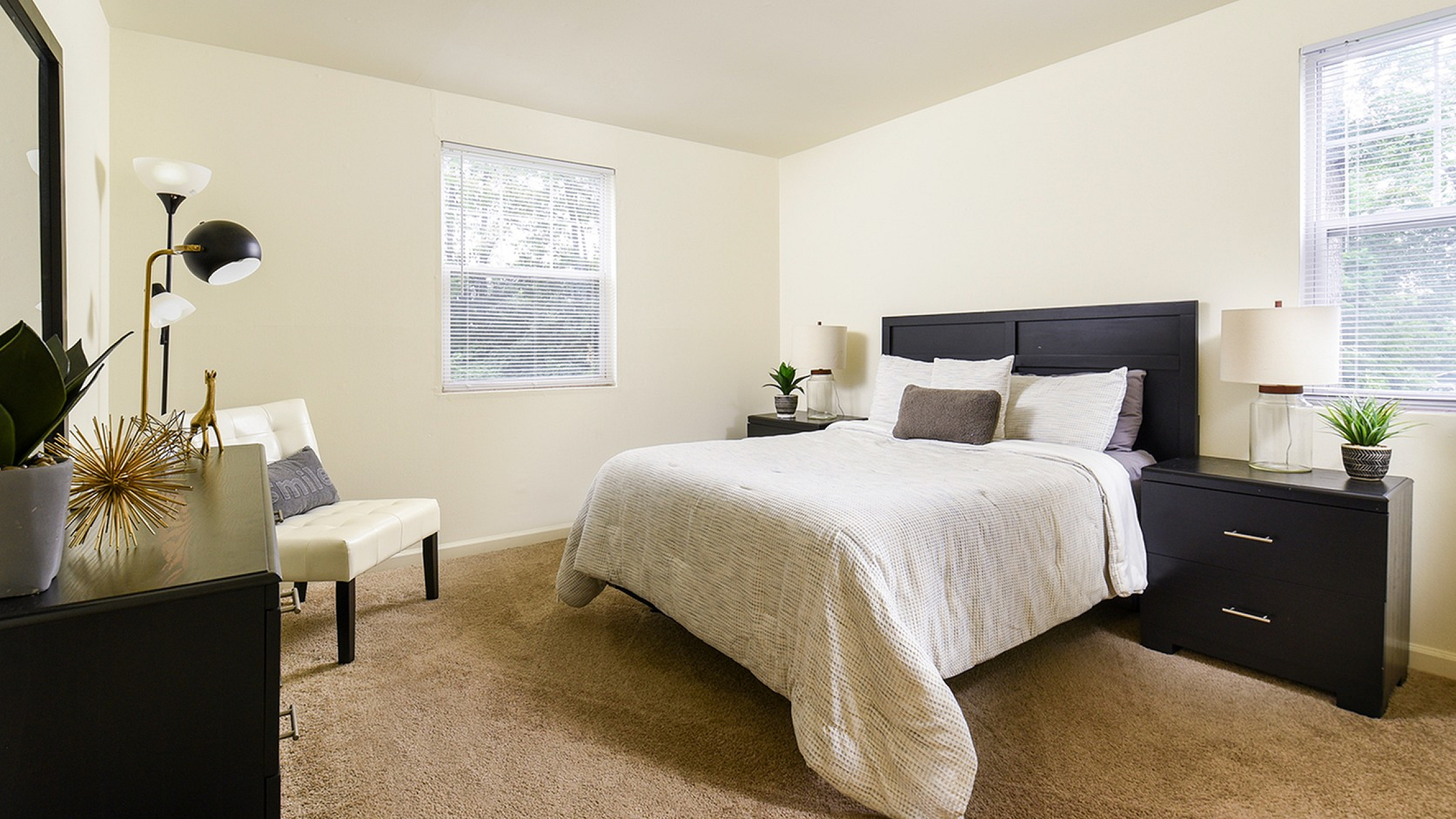 Inviting bedroom with plush carpeting, elegant decor, and abundant natural light.