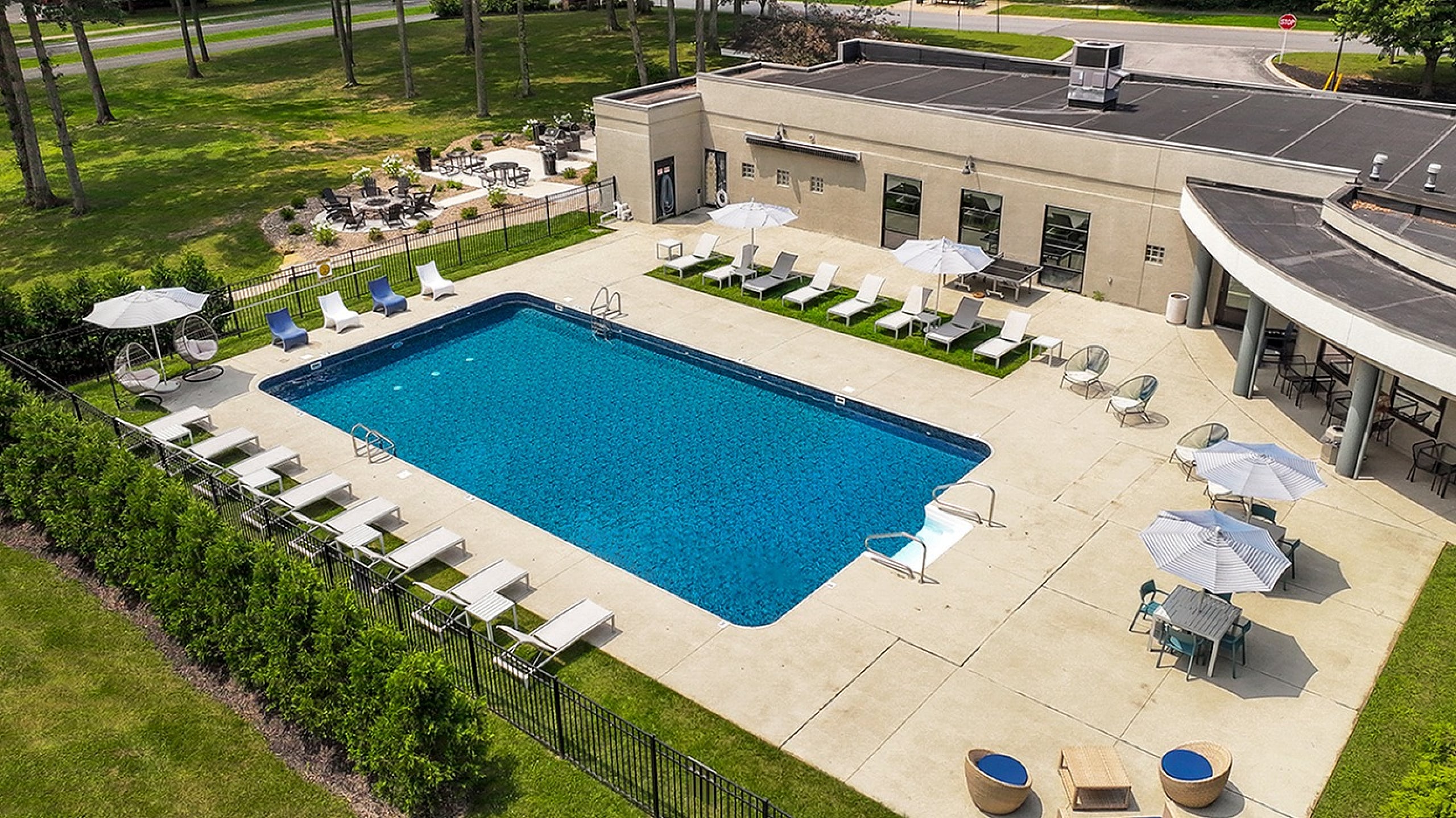 Inviting outdoor oasis with a sparkling blue swimming pool, surrounded by elegant lounge chairs and shaded seating areas, perfect for relaxation.