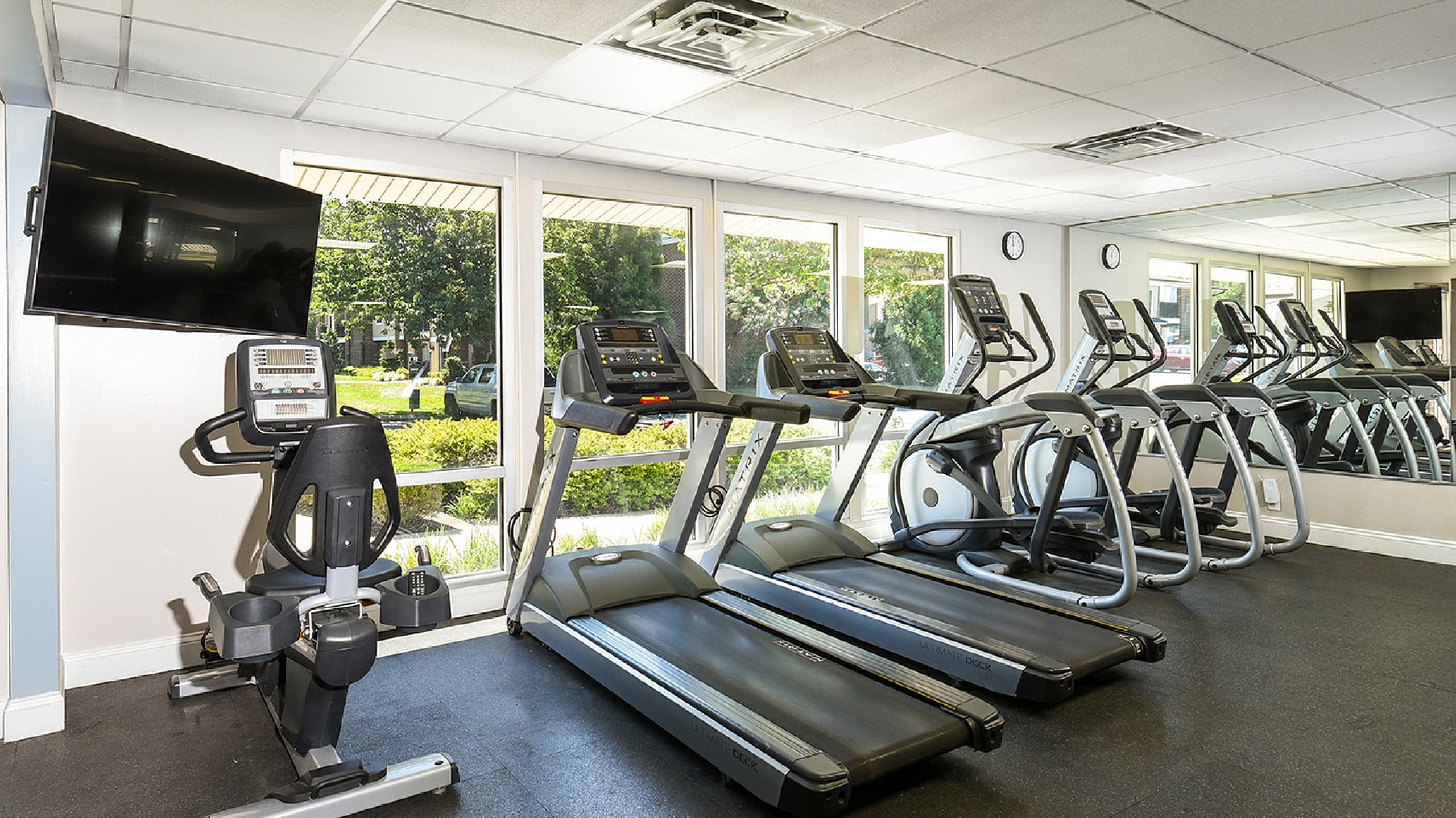 Modern fitness center with state-of-the-art exercise equipment and natural light through large windows.