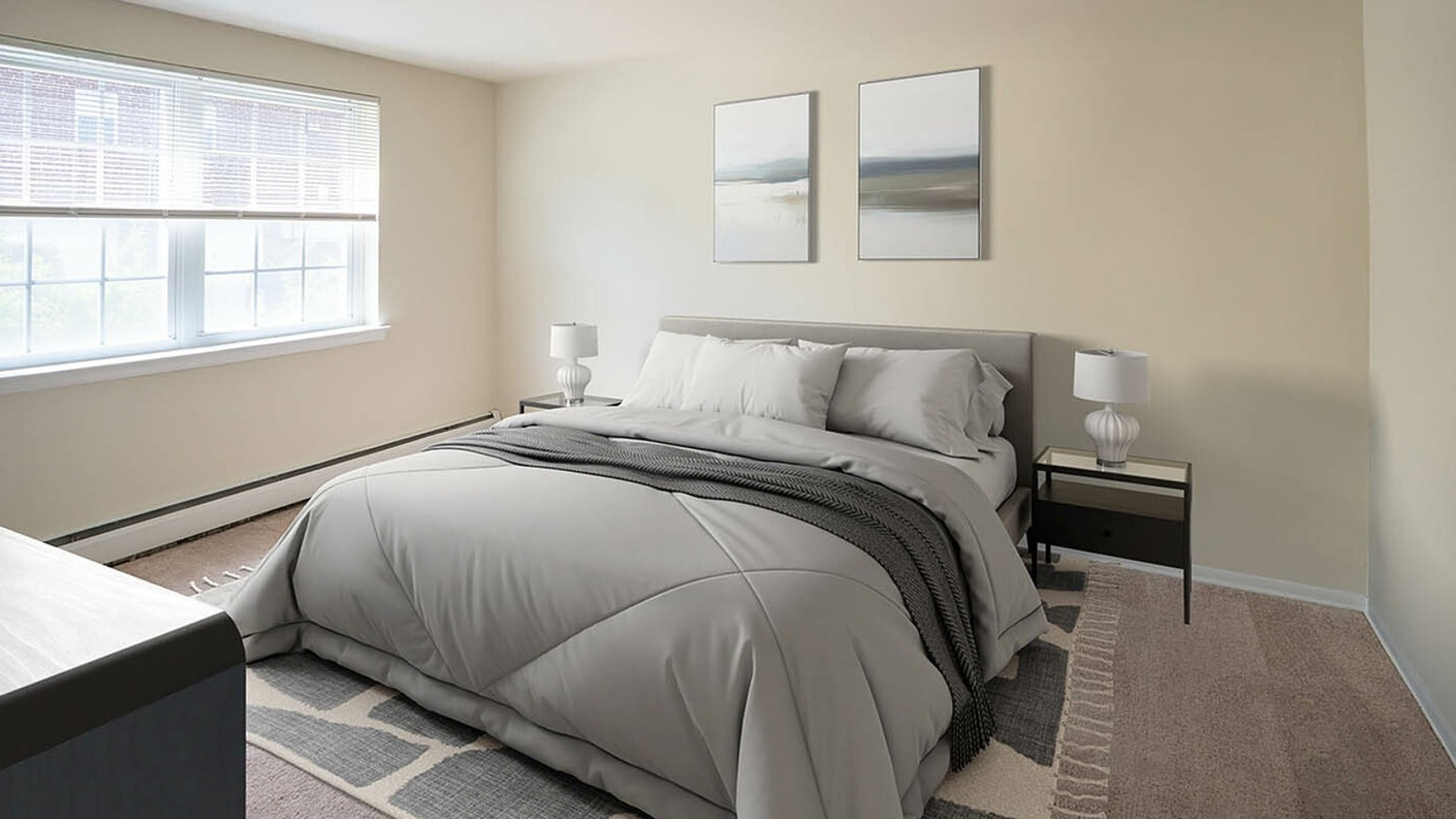 Inviting bedroom with soft gray bedding, elegant decor, and large sunlit window perfect for relaxation.