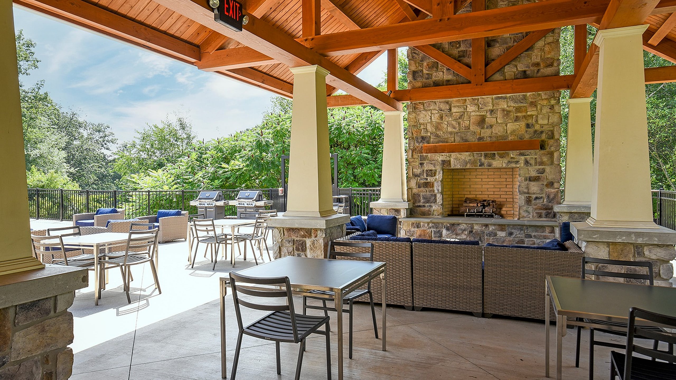 Charming outdoor patio with a cozy stone fireplace, stylish seating, and lush greenery, perfect for relaxation and entertaining.
