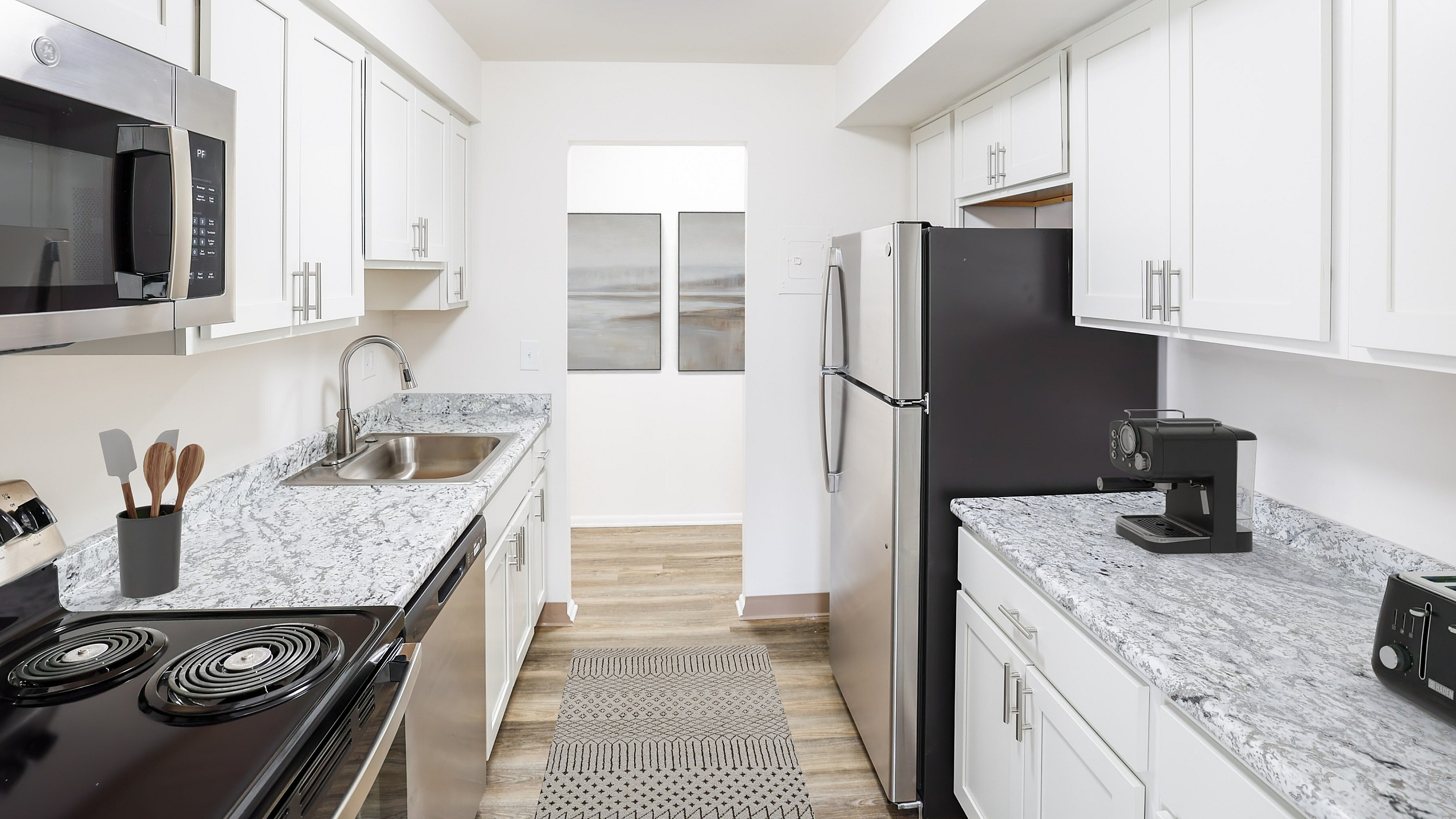 Modern kitchen with sleek stainless steel appliances, elegant white cabinetry, and stylish granite countertops.